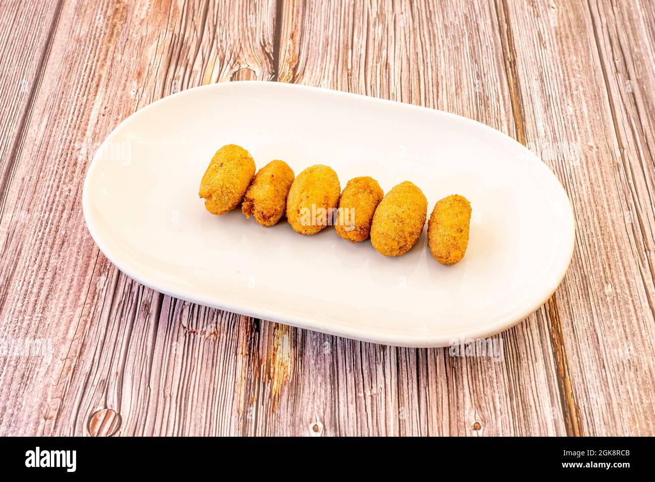 Ham croquettes with bechamel ready to serve as a tapa on a wooden table