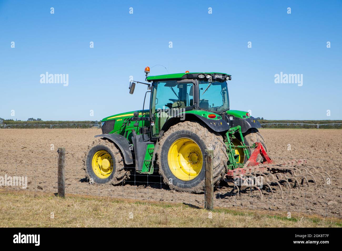 Canterbury, New Zealand, September 3 2021: A John Deere tractor with a plough attached sits in a rural field after preparing a field for sowing Stock Photo