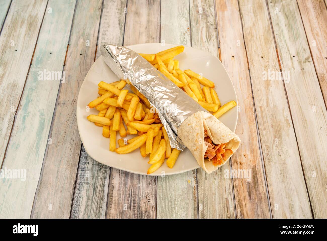typical durum prepared in a kebab restaurant with a side of french fries and aluminum foil to roll up the omelette Stock Photo