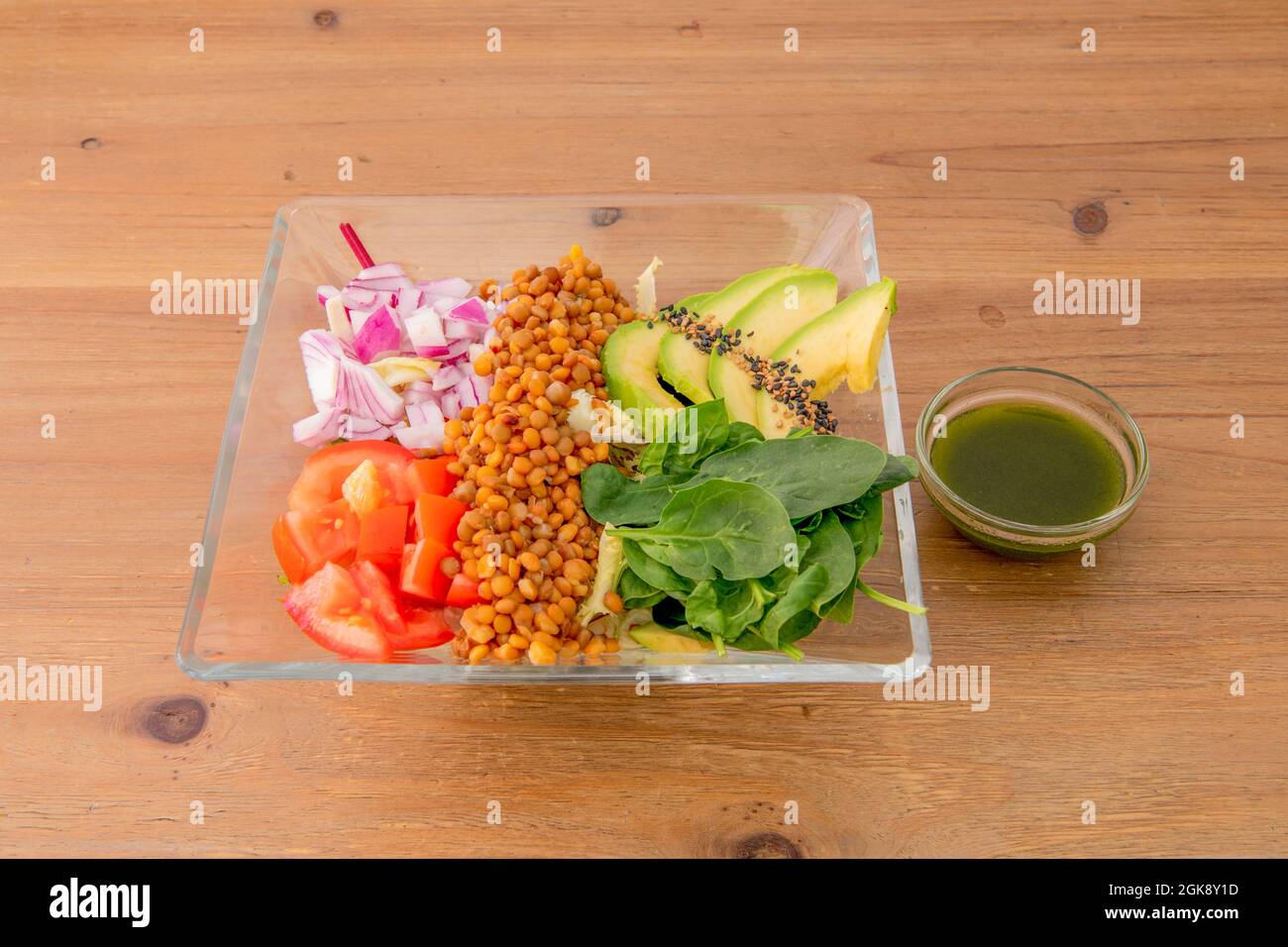 salad with Mediterranean and American ingredients. Green-yellow avocado, green spinach, red onion, stewed lentils, chopped tomato, sesame and poppy se Stock Photo