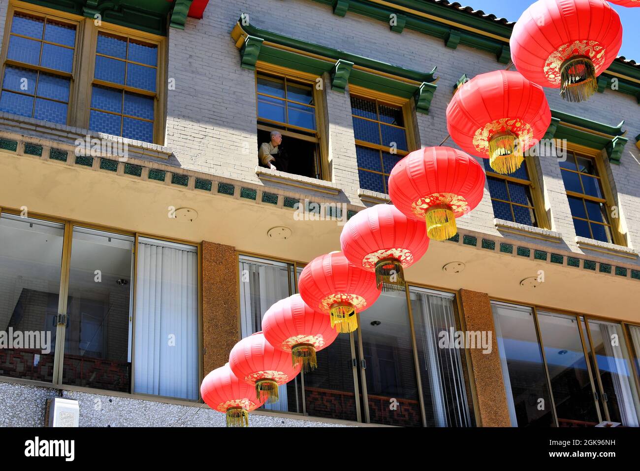 Row of Chinese lanterns and apartment buildings in the background with Buddhist monk looking out