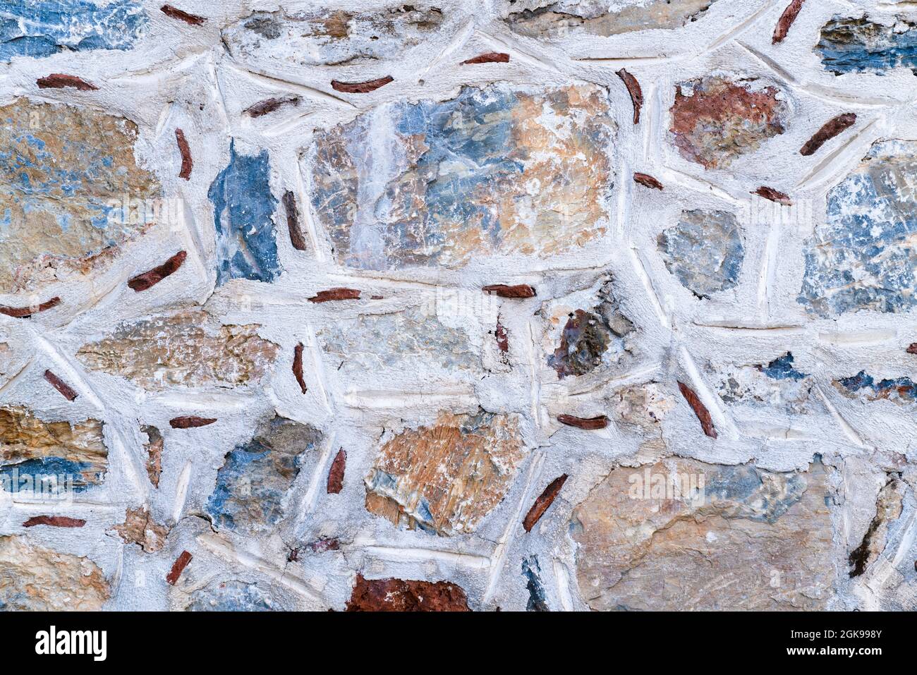 Background texture of wall made of colored stones with white putty. Ancient method of masonry walls. Stock Photo