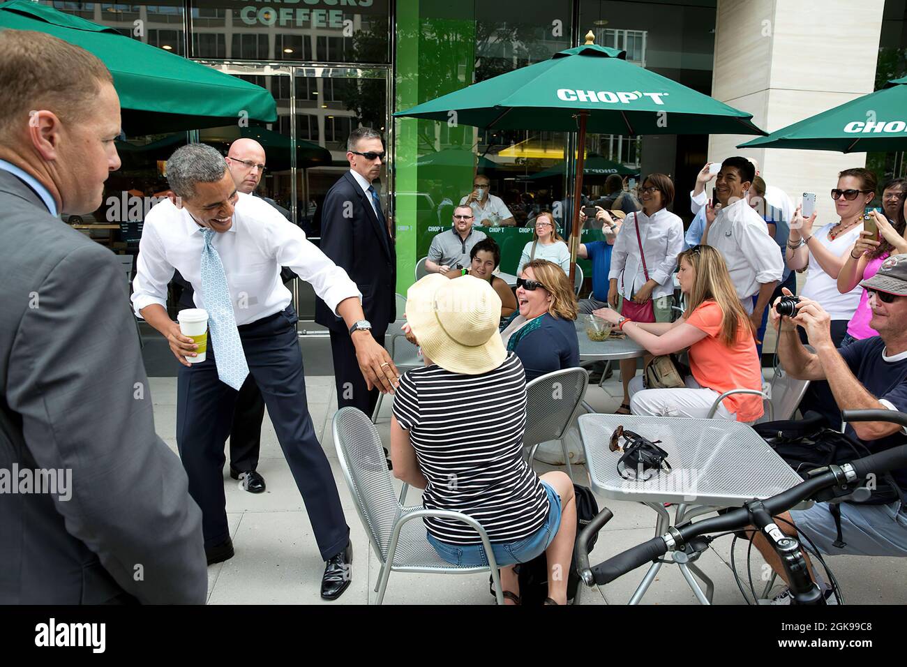 President Barack Obama greets people sitting outside a Chop't restaurant after dropping by a Starbucks on Pennsylvania Avenue in Washington, D.C., June 9, 2014. (Official White House Photo by Pete Souza) This official White House photograph is being made available only for publication by news organizations and/or for personal use printing by the subject(s) of the photograph. The photograph may not be manipulated in any way and may not be used in commercial or political materials, advertisements, emails, products, promotions that in any way suggests approval or endorsement of the President, the Stock Photo