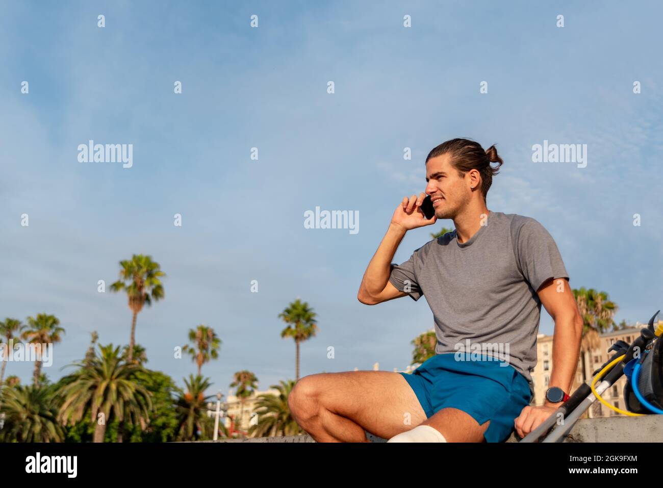 Young latin man with crutches using mobile phone after doing exercise Stock Photo