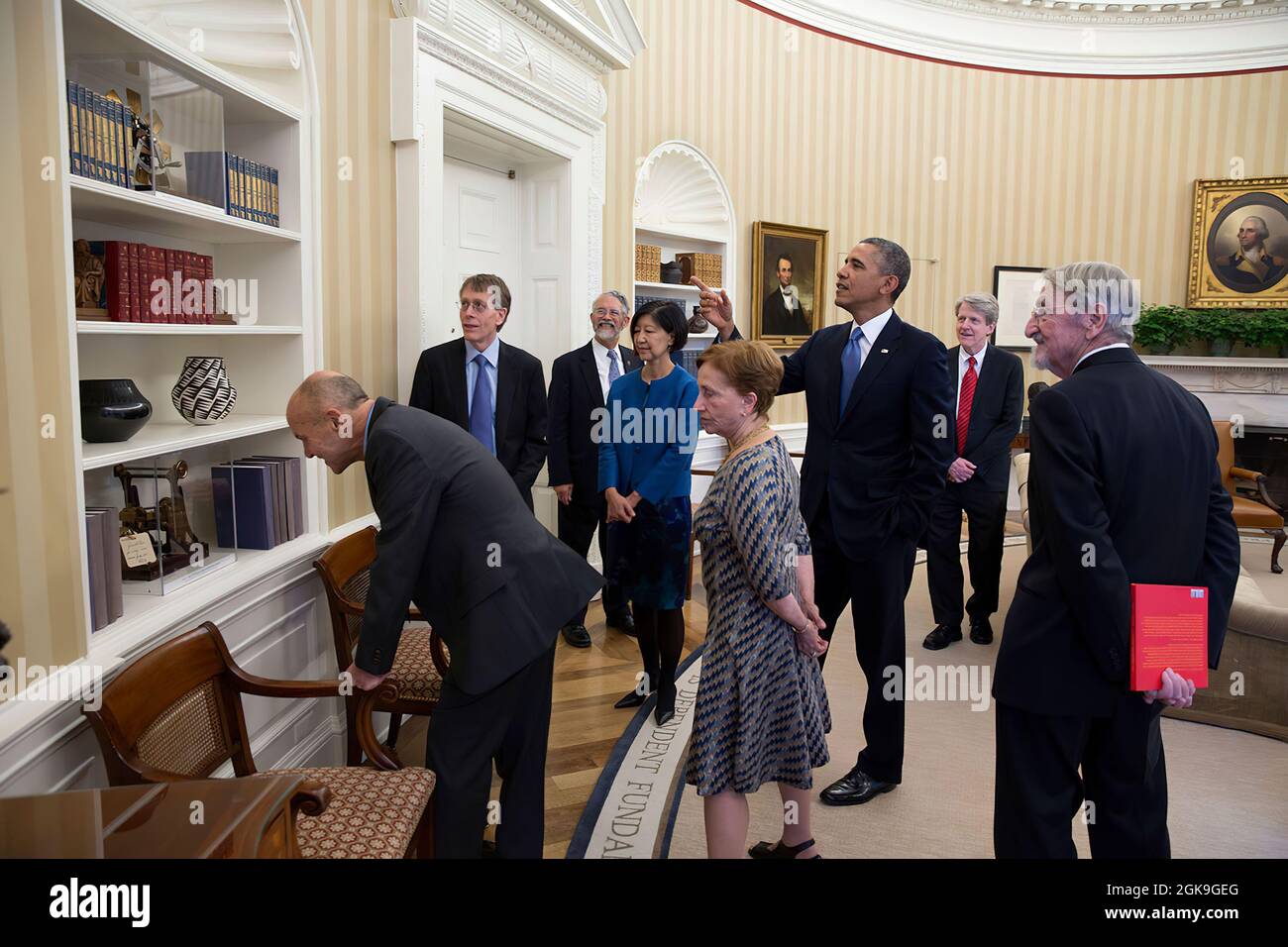 President Barack Obama points out several patent models while meeting with the 2013 American Nobel laureates and their spouses in the Oval Office, Nov. 19, 2013. (Official White House Photo by Pete Souza) This official White House photograph is being made available only for publication by news organizations and/or for personal use printing by the subject(s) of the photograph. The photograph may not be manipulated in any way and may not be used in commercial or political materials, advertisements, emails, products, promotions that in any way suggests approval or endorsement of the President, th Stock Photo