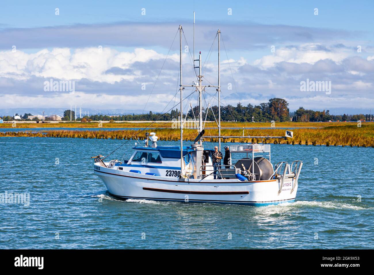 Small commercial fishing vessel leaving Ladner Harbour en route to the Strait of Georgia in British Columbia Canada Stock Photo
