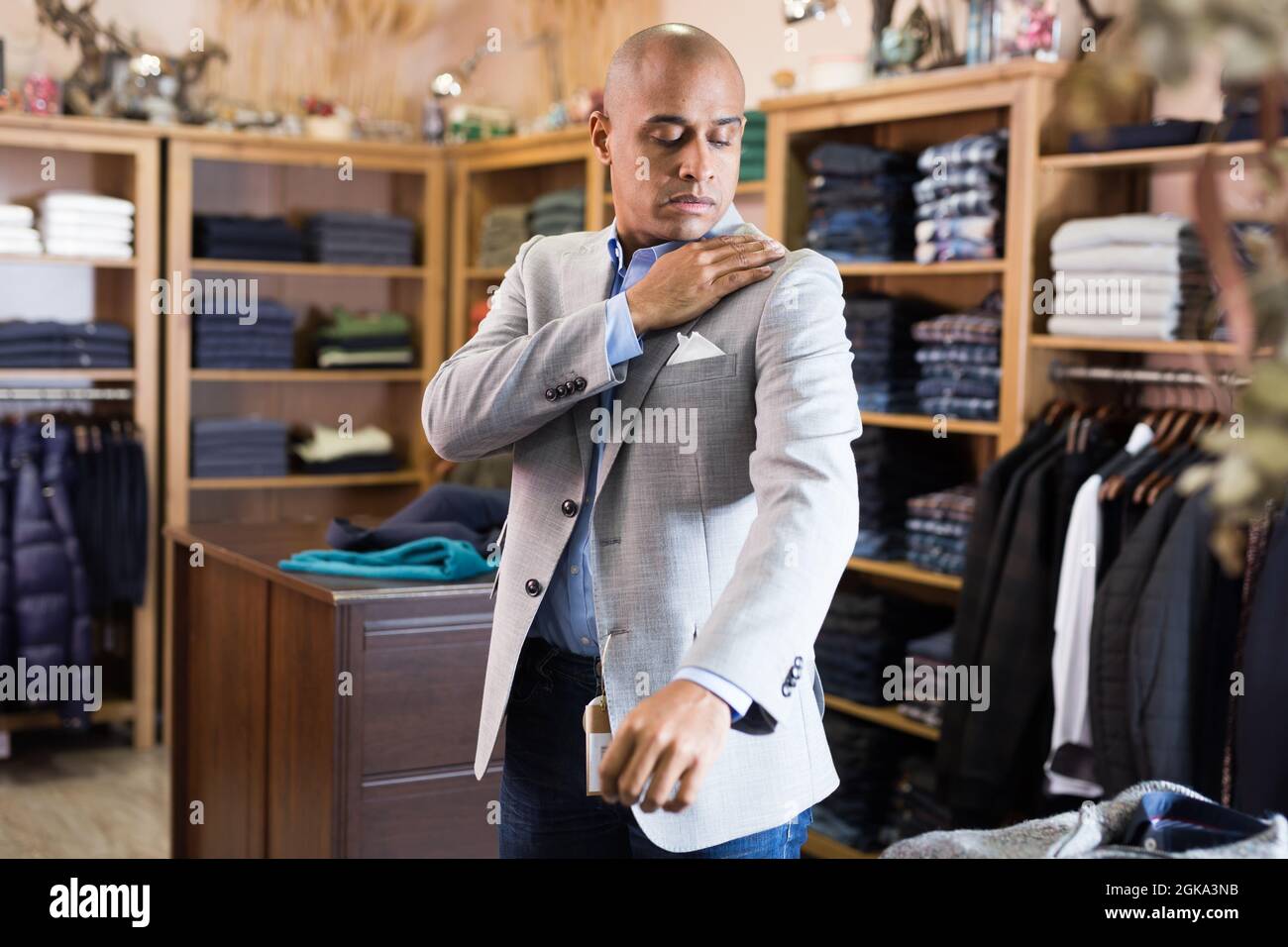 Man choosing suit jacket in clothing store Stock Photo - Alamy