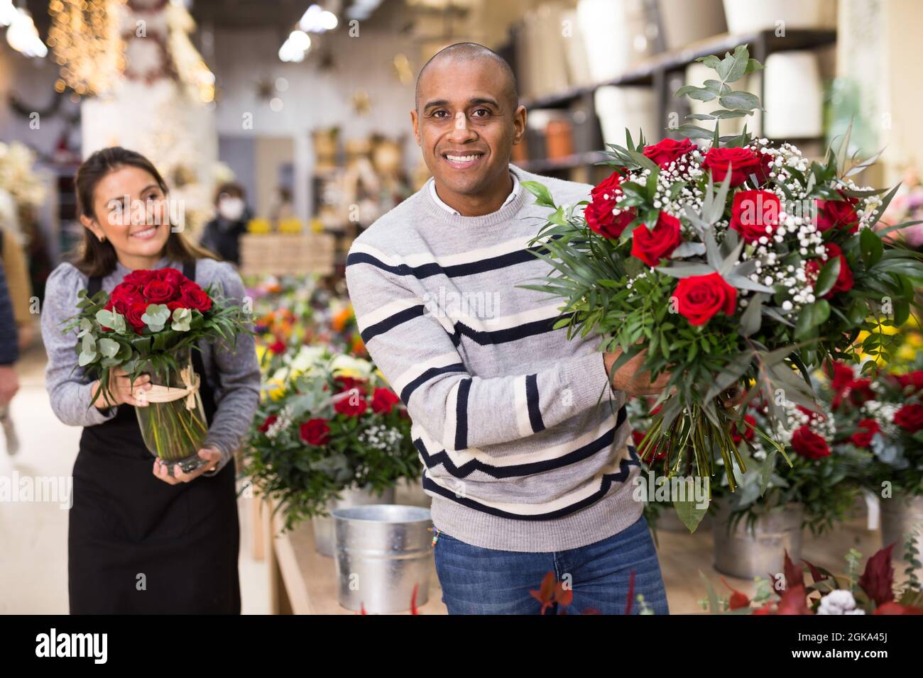 Seller offering gift flower arrangement with roses to male buyer Stock ...