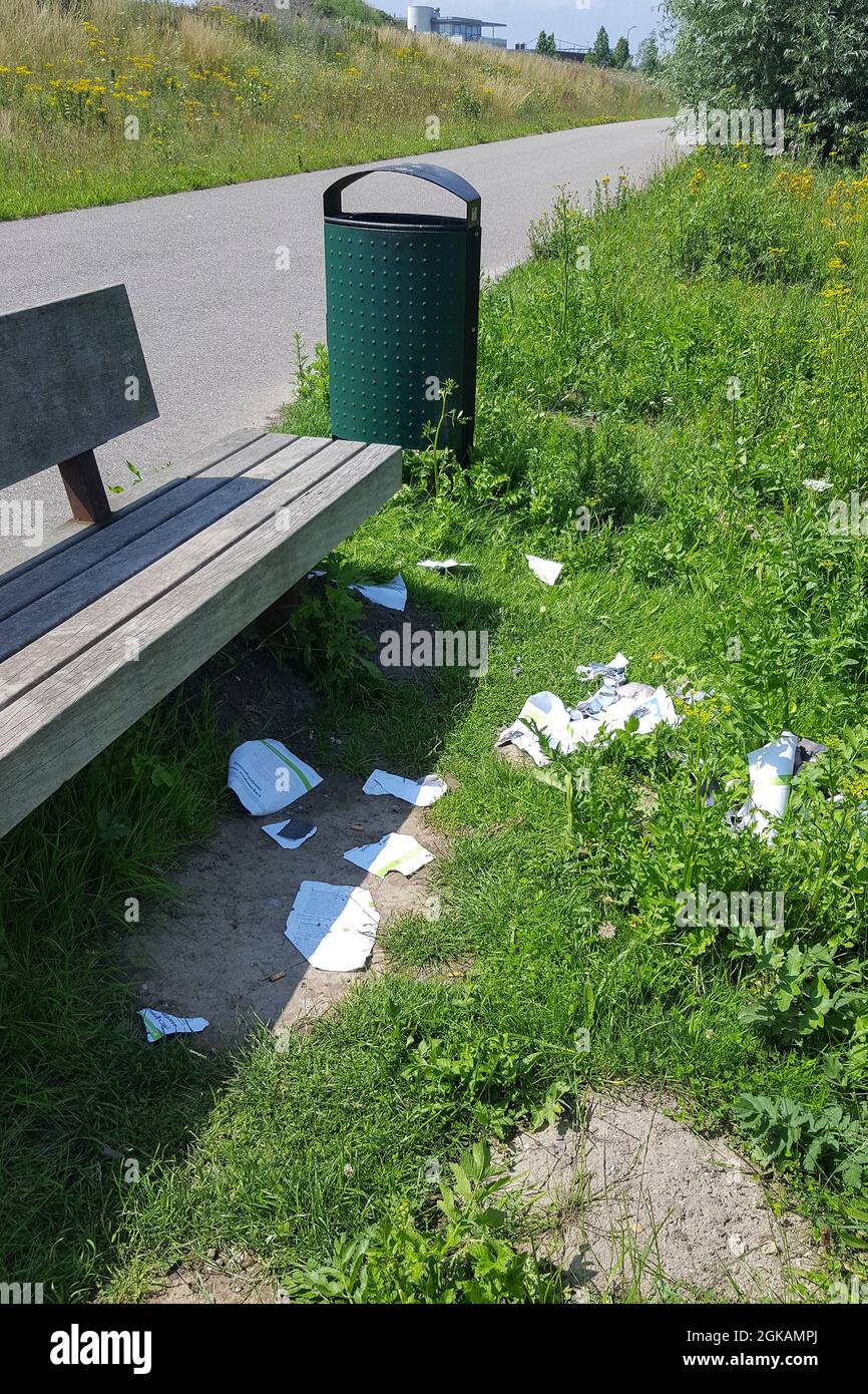 Mess around an outside bench with wastebasket Stock Photo