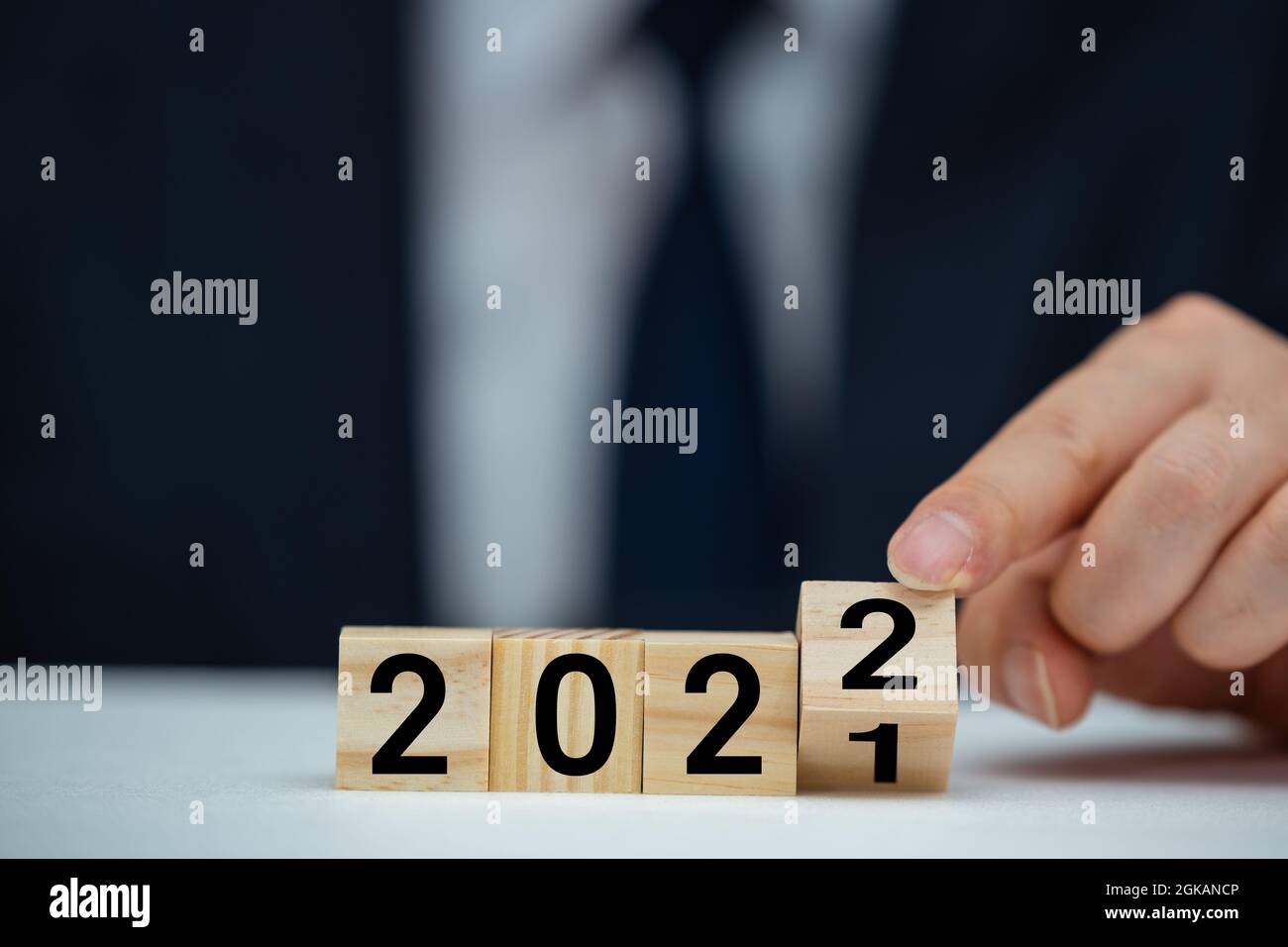 Businessman hand holding wooden cube with flip over block 2021 to 2022 text on table background. Stock Photo