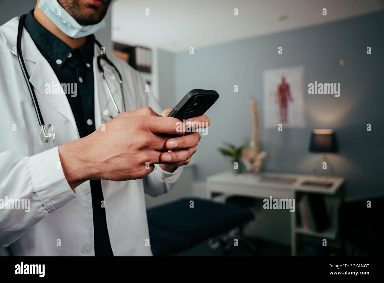 Mixed race male nurse standing in office texting on cellular device Stock Photo