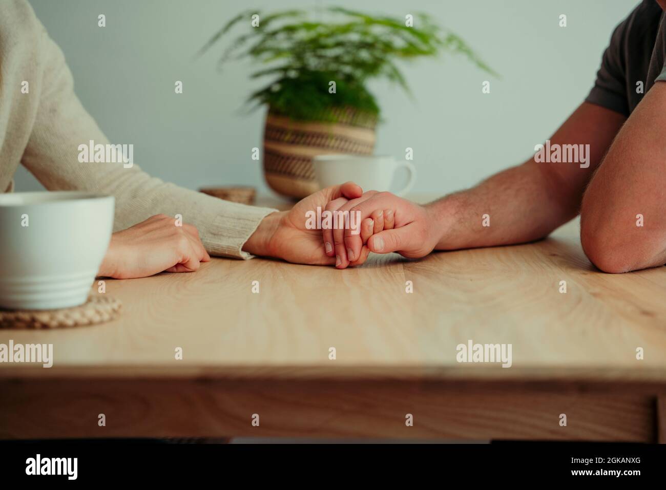 Close up caucasian couple sitting at table holding hands  Stock Photo