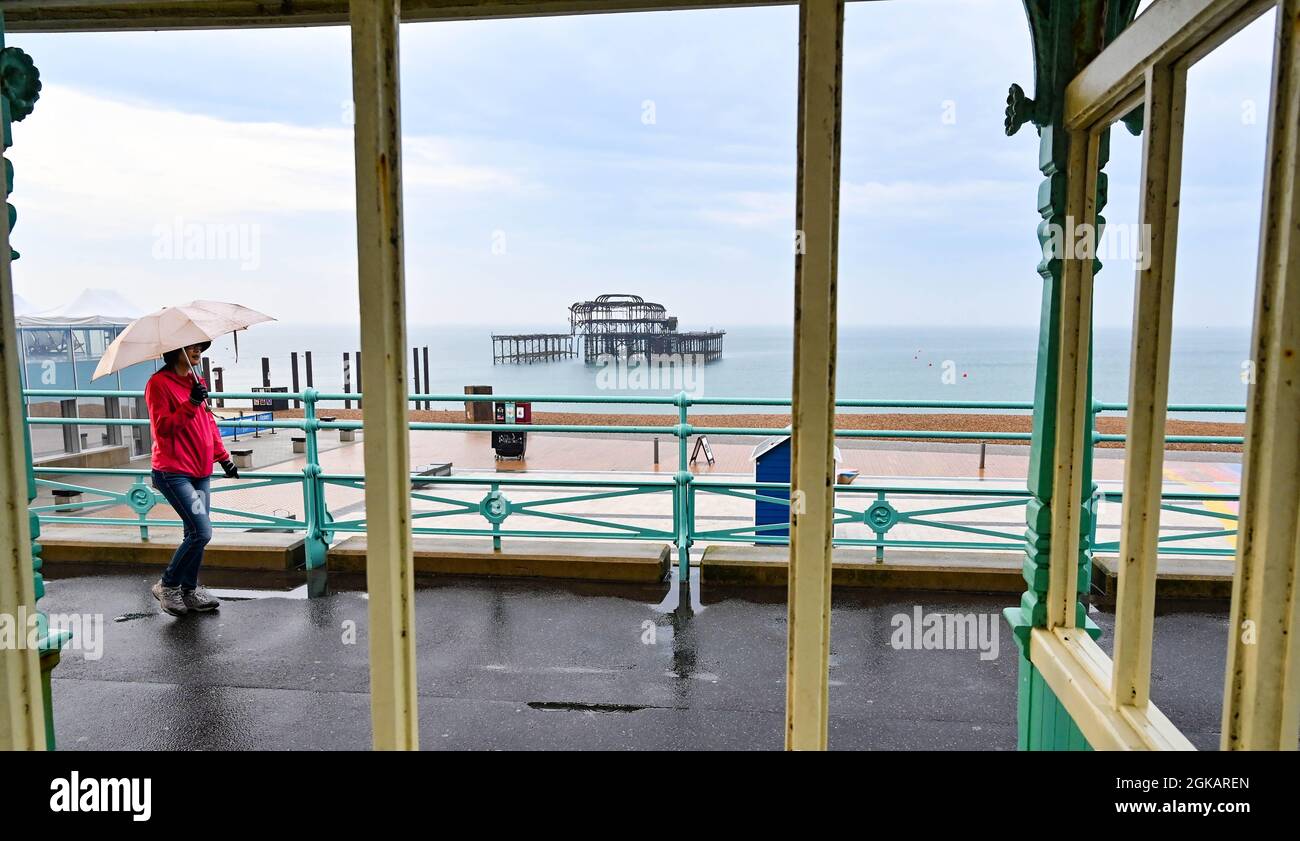 Brighton UK 14th September 2021 - An early morning walker with an umbrella in heavy rain by Brighton's West Pier with over a months rainfall forecast for some parts of Britain today  : Credit Simon Dack / Alamy Live News Stock Photo