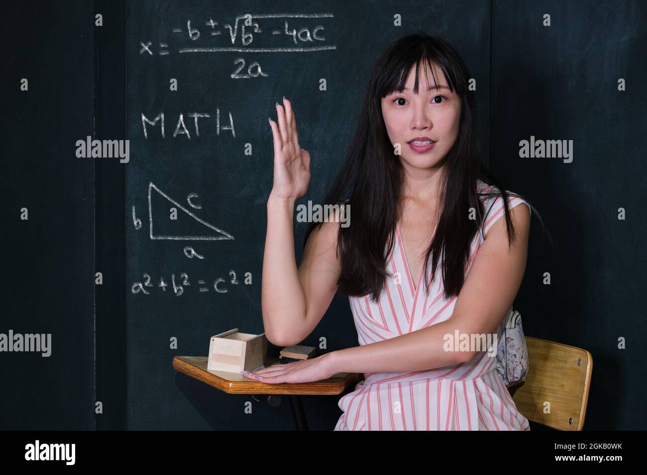 Young asian woman pretending to be a child raise her hand in math class. Stock Photo
