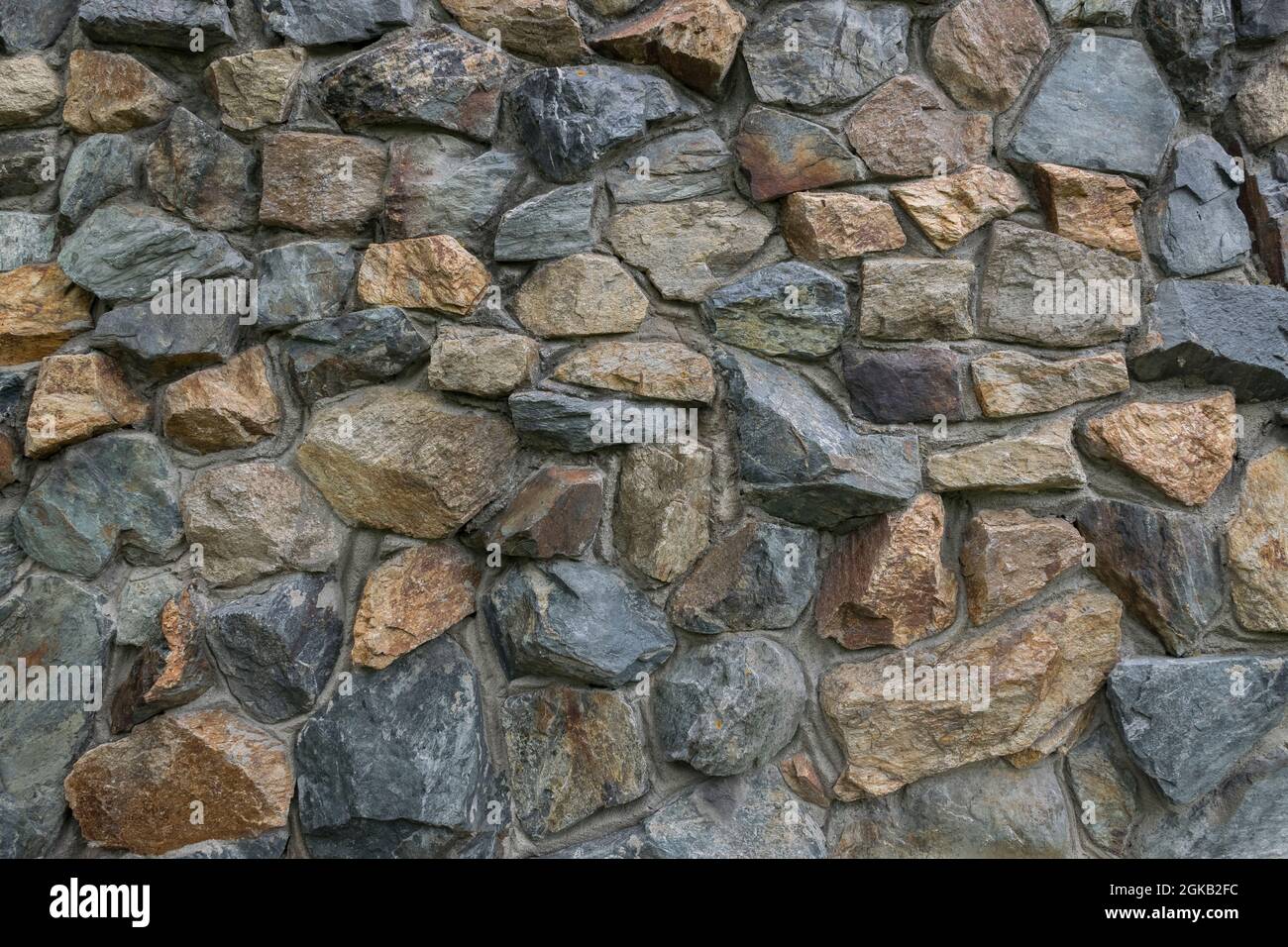 Stone wall exterior texture. Old stone wall with varying sizes , shapes and colored of stones. Stock Photo