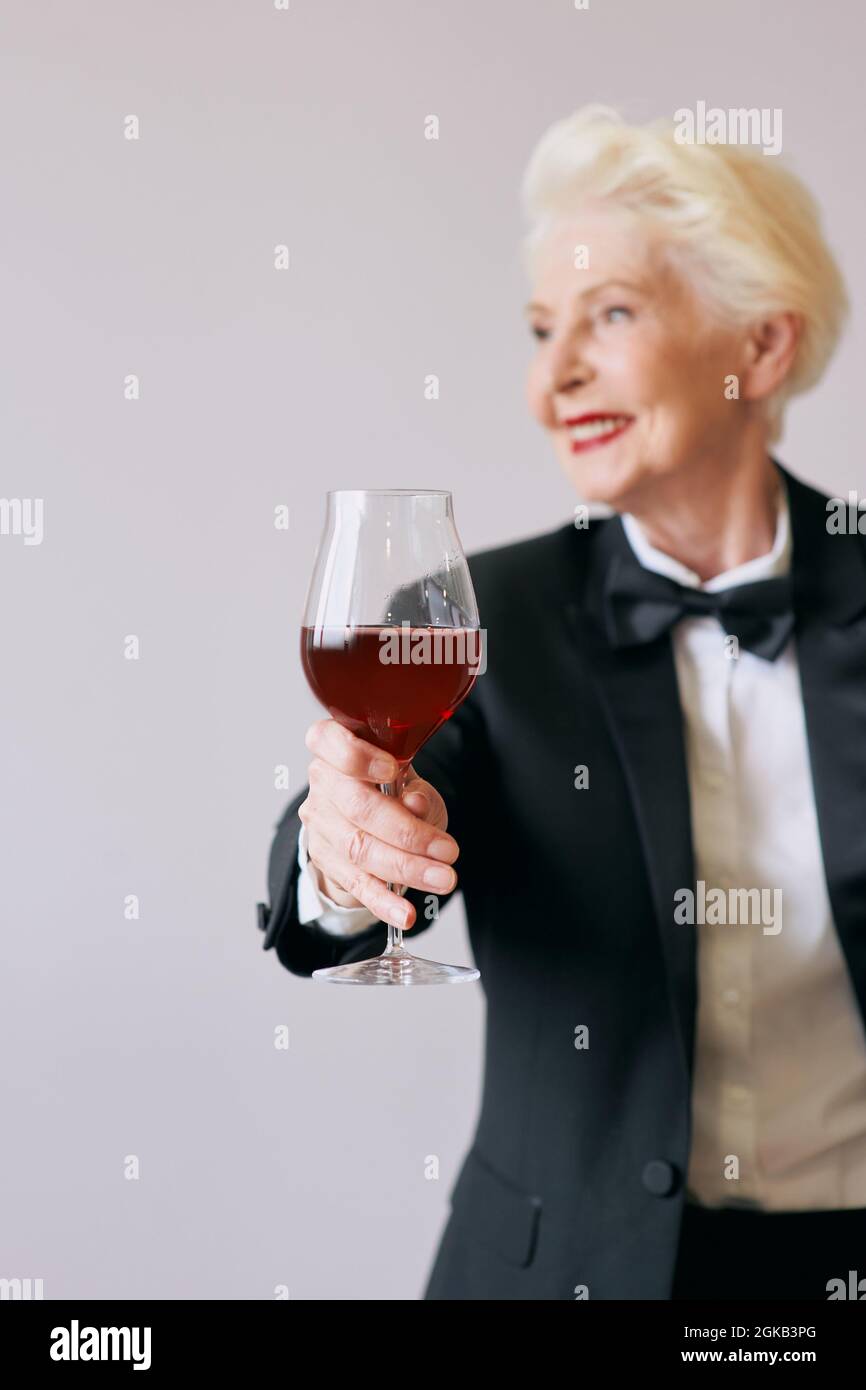 stylish senior sommelier woman in tuxedo with glass or red wine. Beverage, mature, style concept Stock Photo