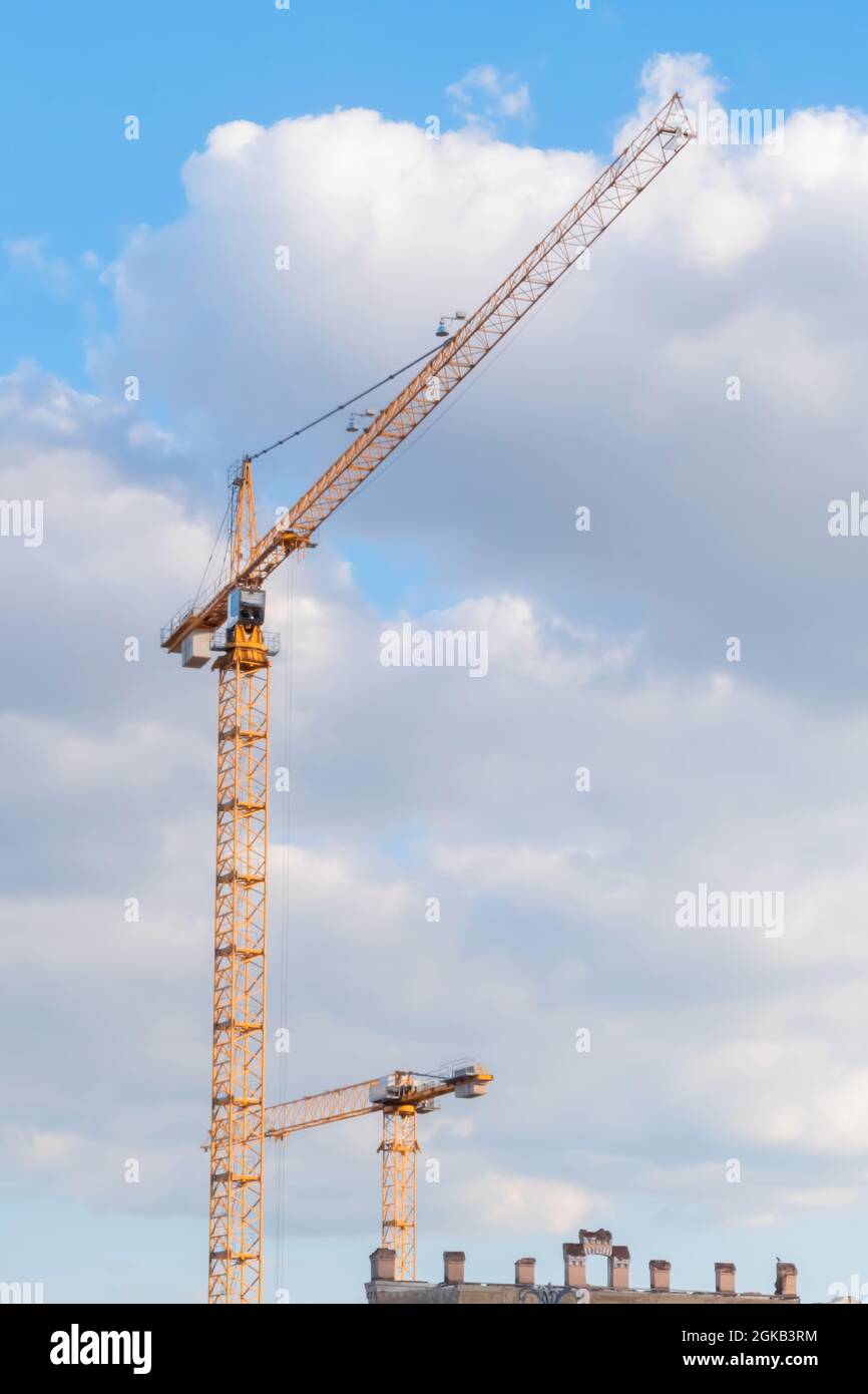 Yellow tower construction cranes against cloudy sky Stock Photo