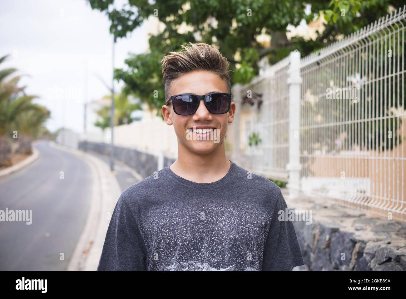 Portrait of cheerful handsome teenage boy wearing sunglasses and