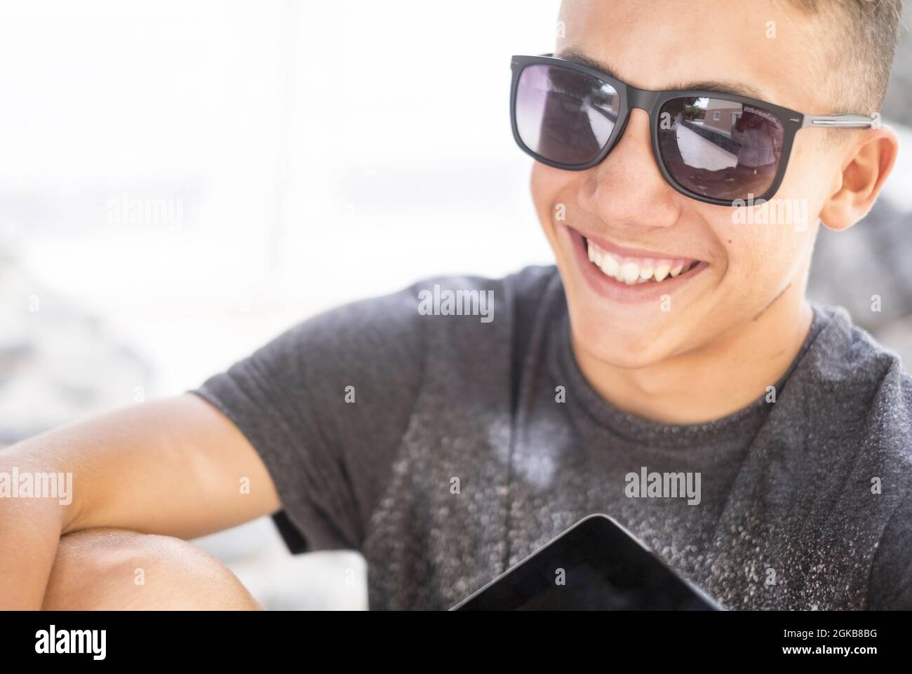 Portrait of cheerful handsome teenage boy wearing sunglasses and