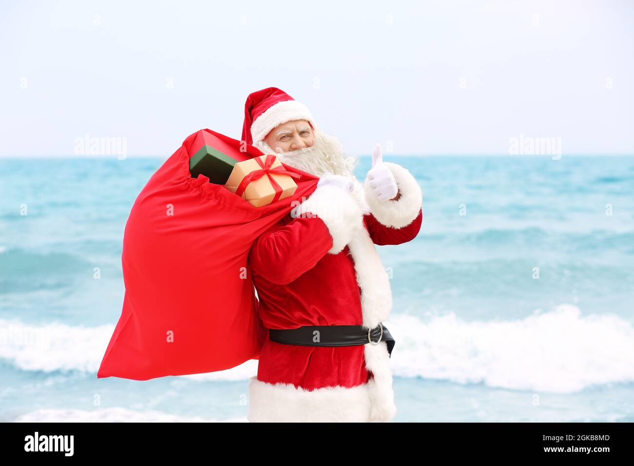 Authentic Santa Claus with big red bag full of gifts on sea background ...