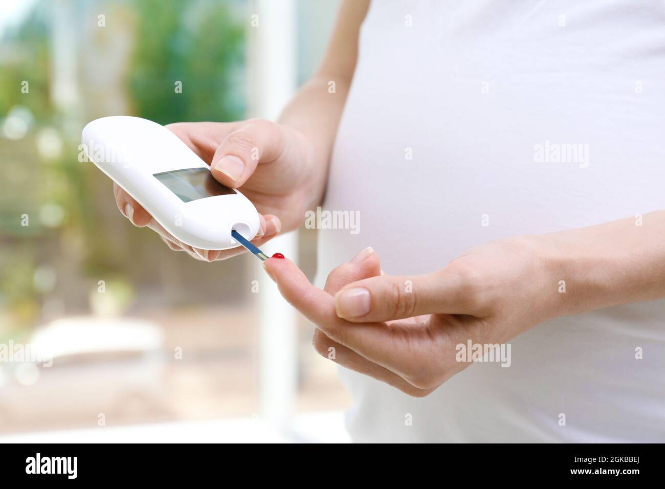 Pregnant woman testing glucose level with digital glucometer Stock ...