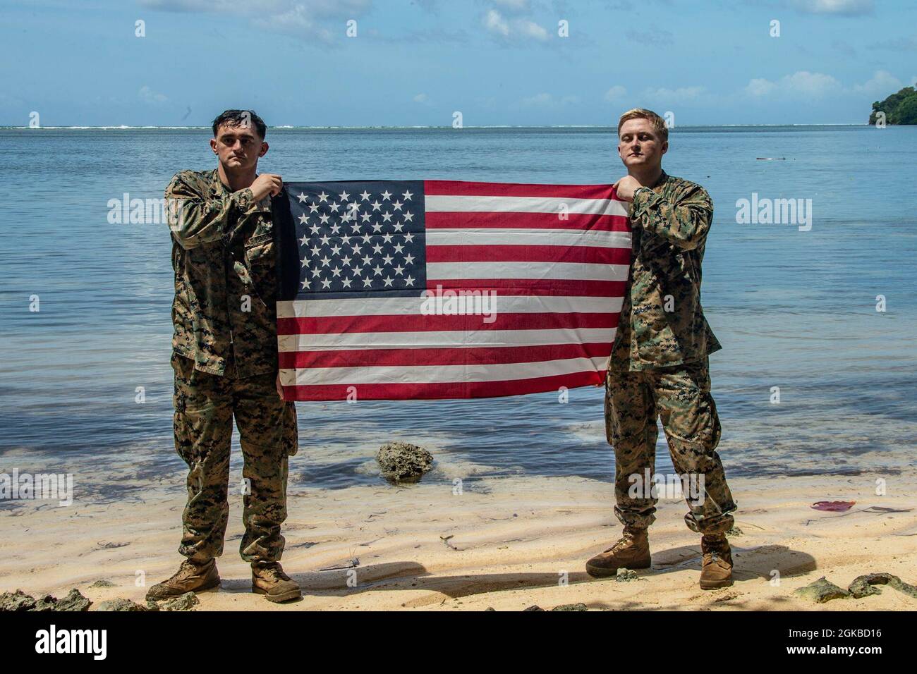 U.S. Marines with the 31st Marine Expeditionary Unit (MEU) hold a United States flag at White Beach, the location that the 1st Marine Division landed at during World War II, on the Island of Peleliu in the Republic of Palau, March 3, 2021. The 31st MEU is operating aboard ships of the Amphibious Squadron 11 in the 7th fleet area of operations to enhance interoperability with allies and partners and serve as a ready response force to defend peace and stability in the Indo-Pacific region. Stock Photo