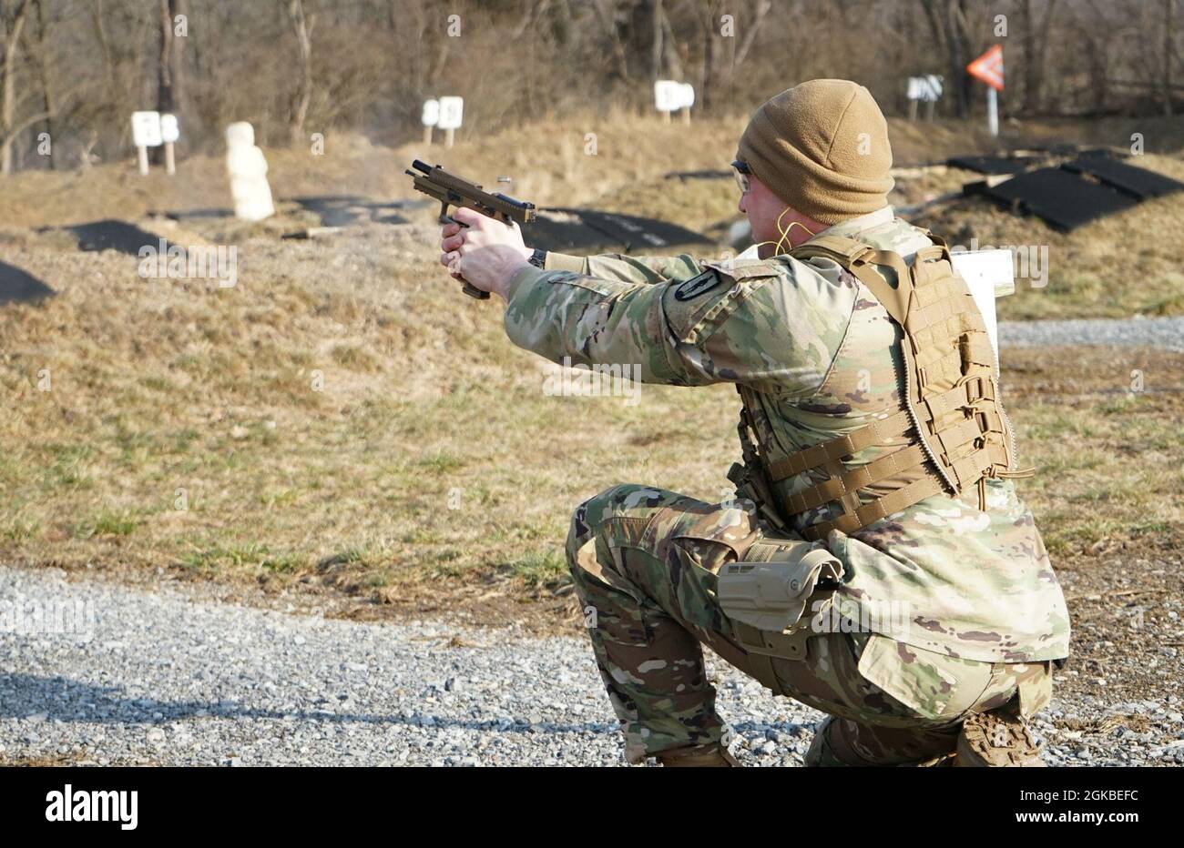 Staff Sgt. Dylan Pitetti, a Soldier from Pennsylvania Joint Force Headquarters, engages a pop up target from the kneeling position during the M17 pistol qualification part of the Pennsylvania Army National Guard's Best Warrior Competition on March 4, 2021, at Fort Indiantown Gap, Pa. The range portion of the competition consisted of qualification with the M4 carbine, M17 pistol, and M500 shotgun. Stock Photo
