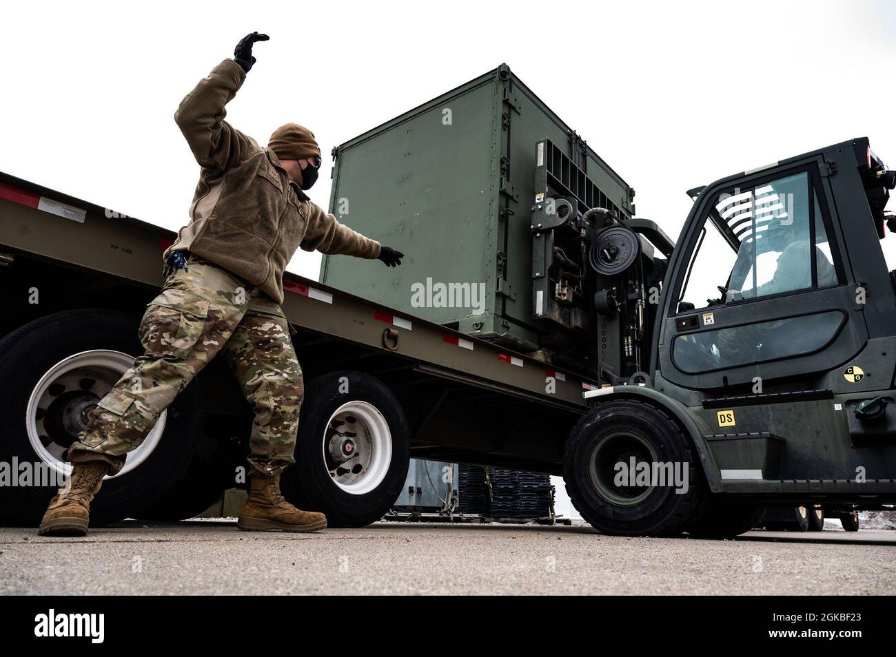 Staff Sgt. Timothy Shultz, 911th Logistics Readiness Squadron ground transportation specialist, directs Senior Airman Thomas Luther, 911th LRS ground transportation specialist, on how to position a conex box on a flatbed trailer while training at the Pittsburgh International Airport Air Reserve Station, Pennsylvania, March 4, 2021. The ground transportation specialists are training for situations they may encounter while deployed. Stock Photo