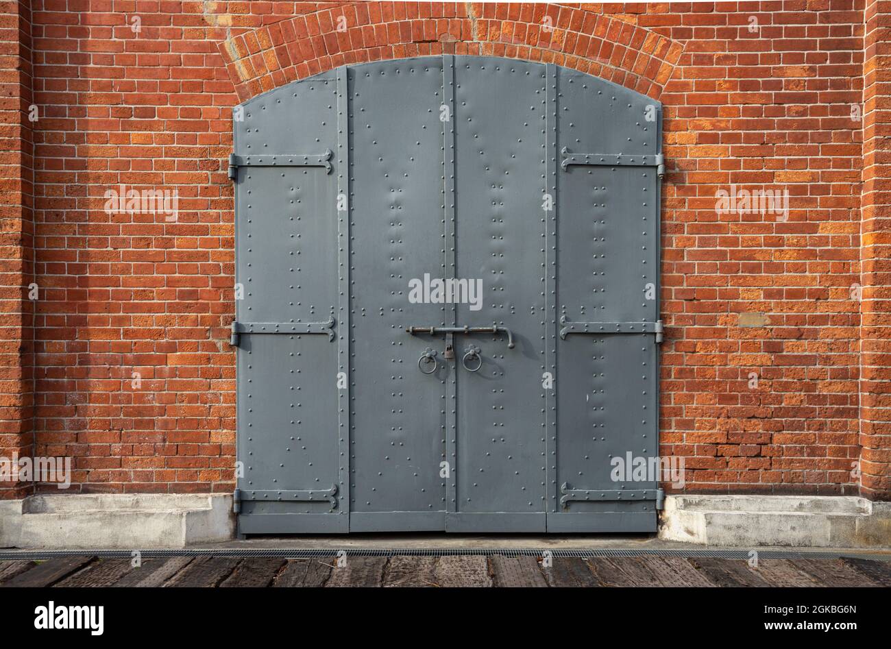 Closed iron gate, door with a padlock in a historic red brick building. Stock Photo