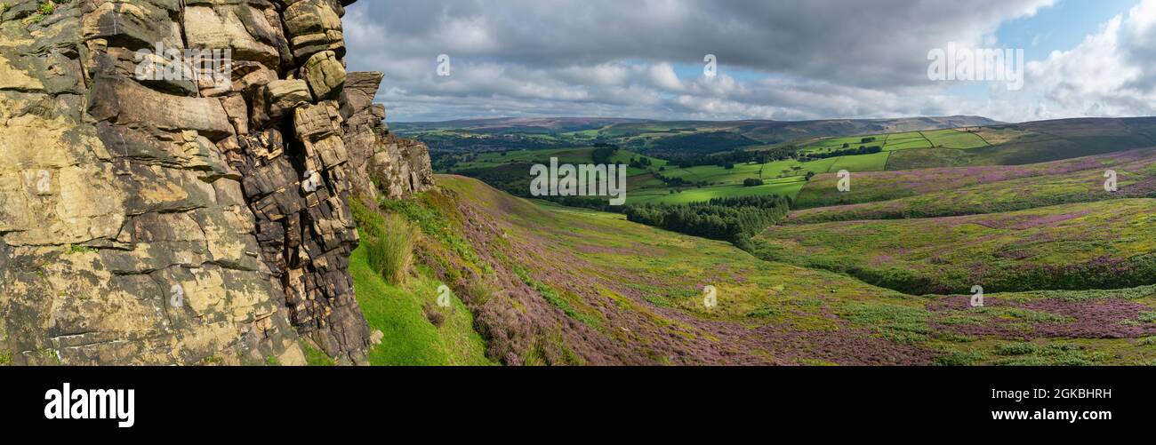 The Worm Stones, a gritstone outcrop in the hills above Glossop in the High Peak, Derbyshire, England. Heather flowering on the moors below. Stock Photo