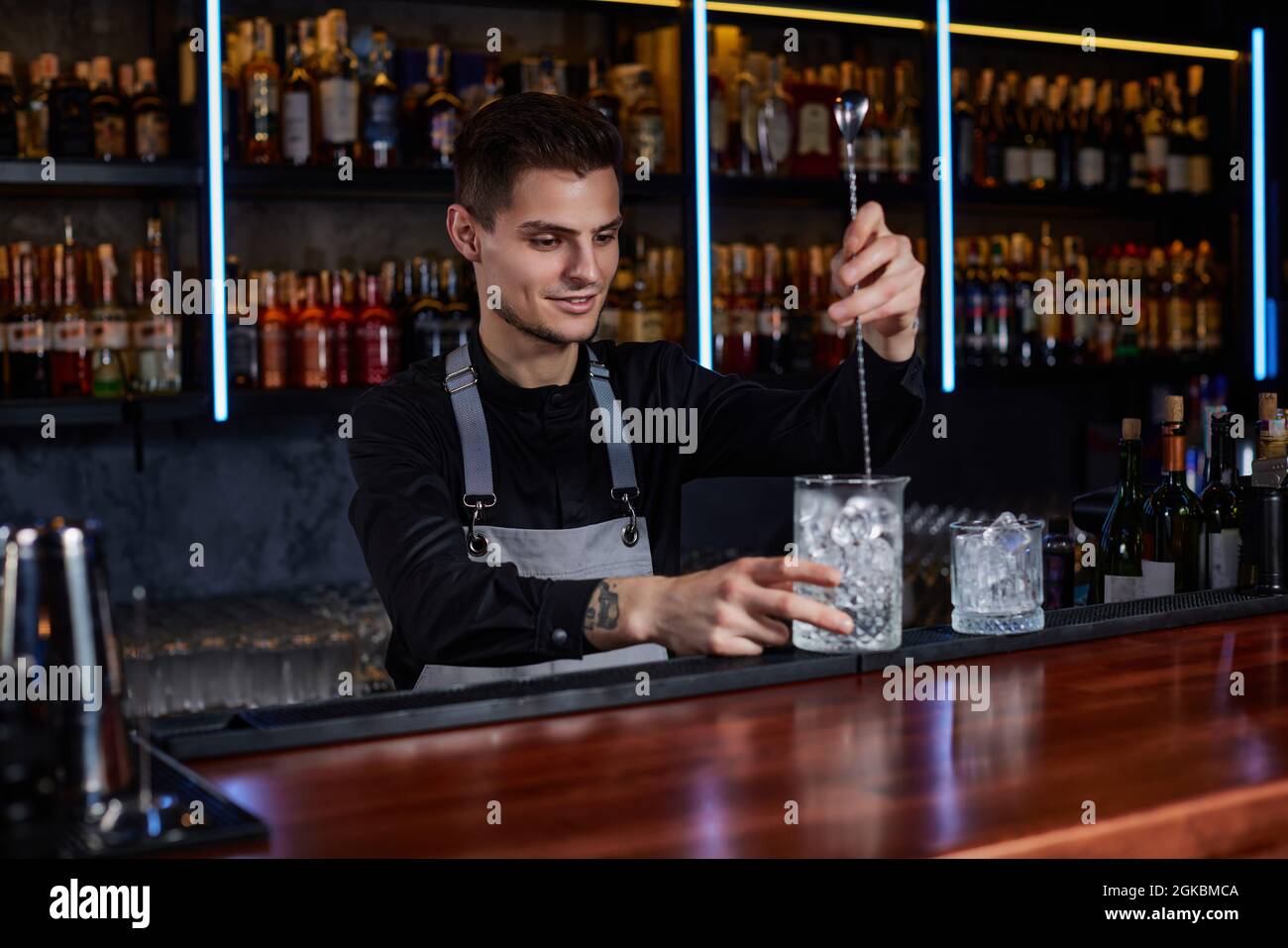 Barman stirring ice cubes in cocktail glass with spoon Stock Photo - Alamy