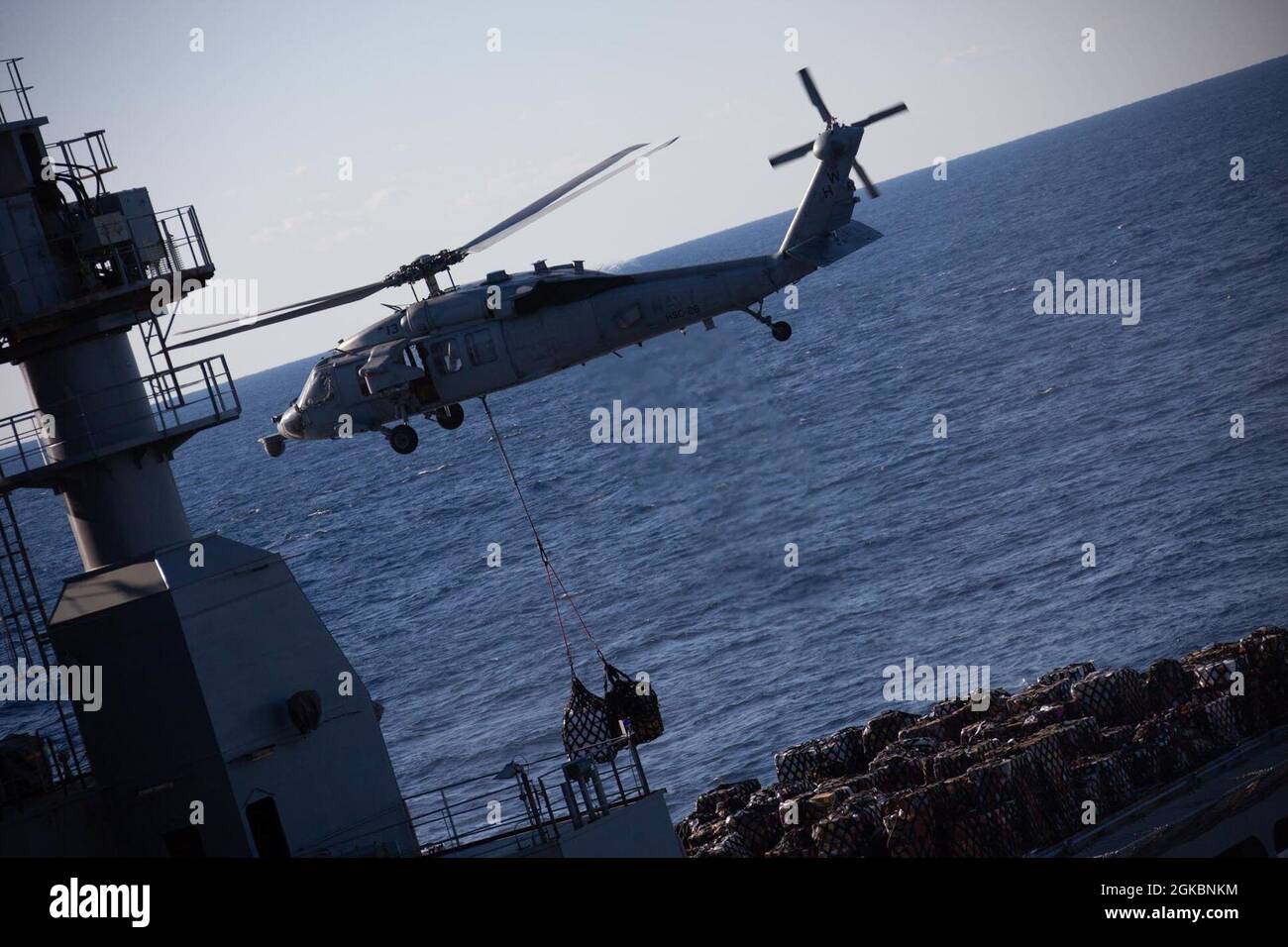 A U.S. Navy MH-60 Sea Hawk lifts cargo in support of a replenishment at sea (RAS) off the Atlantic Coast during Composite Unit Training Exercise (COMPTUEX) on March 5, 2021. COMPTUEX is a month-long training event designed to test the MEU’s capabilities against the full spectrum of military operations. Stock Photo