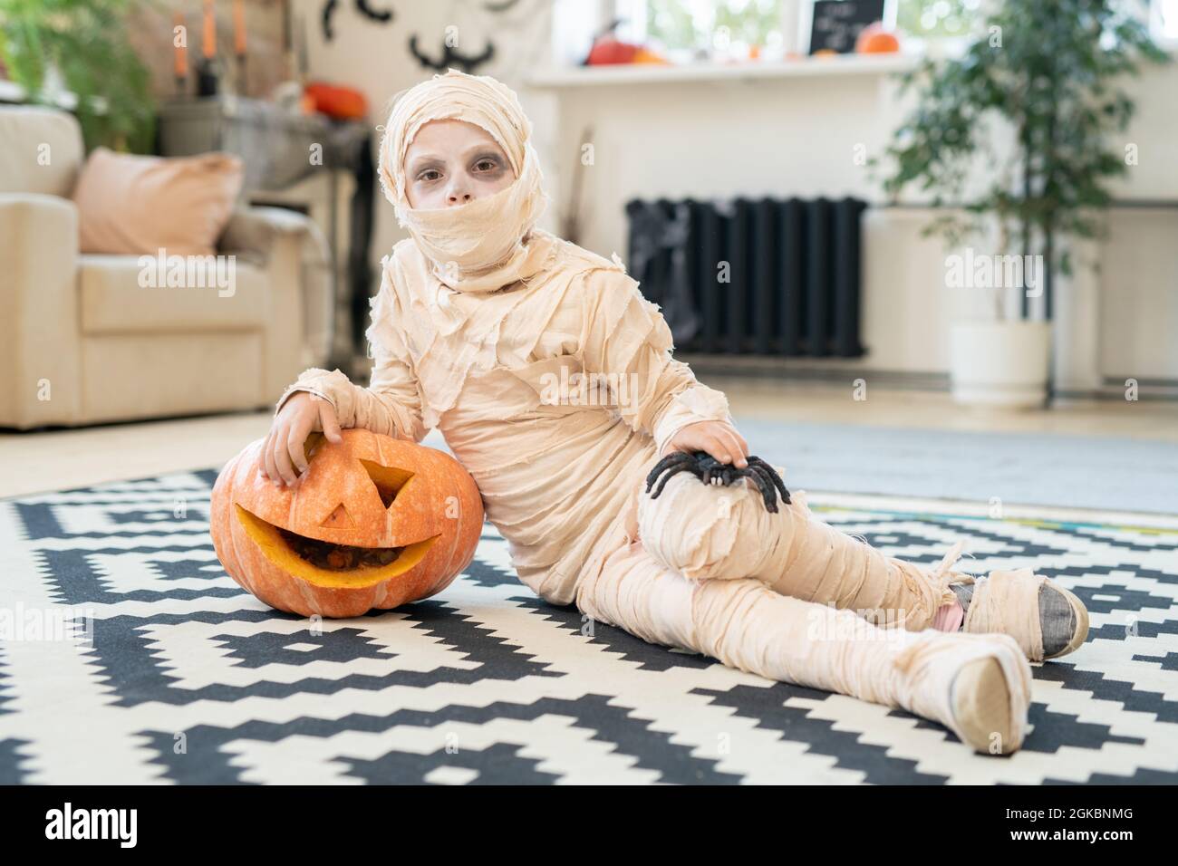 Little boy mummy with spider and jackolantern lying on the