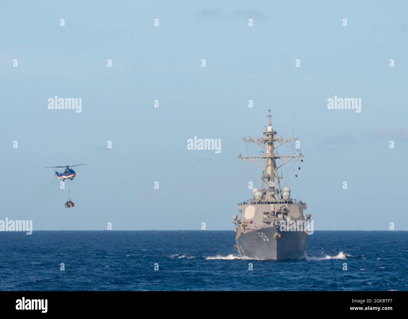 PACIFIC OCEAN (March 6, 2021) An H225 Super Puma helicopter, assigned to the Lewis and Clark-class dry cargo and ammunition ship USNS Charles Drew (T-AKE 10), airlifts supplies to the Arleigh Burke-class guided-missile destroyer USS Russell (DDG 59) during a vertical replenishment March 6, 2021. Russell, part of the Theodore Roosevelt Carrier Strike Group, is on a scheduled deployment to the U.S. 7th Fleet area of operations. As the U.S. Navy’s largest forward-deployed fleet, 7th Fleet routinely operates and interacts with 35 maritime nations while conducting missions to preserve and protect a Stock Photo