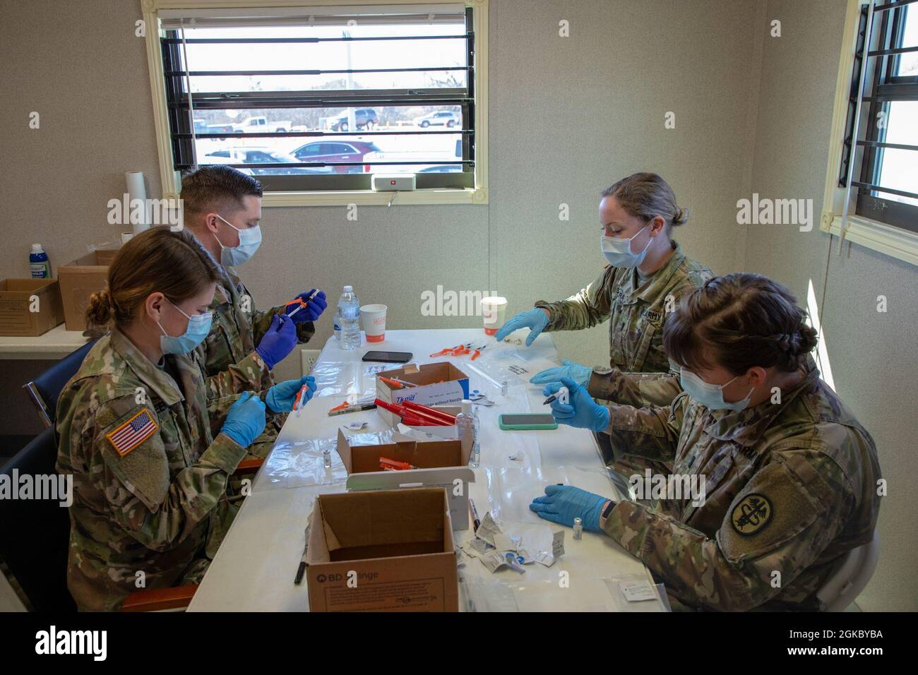 U.S. Army 1st Lt. Abigail Santora, an active-duty medical surgical nurse from Carl R. Darnall Army Medical Center, Fort Hood, Texas, 1st Lt. Erin Adelmann, an active-duty medical oncology nurse from Walter Reed National Military Medical Center, Bethesda, Maryland, 2nd Lt. Martin Gore, an active-duty medical surgical nurse from Walter Reed, and 2nd Lt. Katlyn Keenan, an active-duty medical surgical nurse from Brook Army Medical Center, Fort Sam Houston, Texas, prepare doses of the  COVID vaccine at the Fair Park Community Vaccination Center (CVC) in Dallas, on March 8, 2021. During this  Women’ Stock Photo