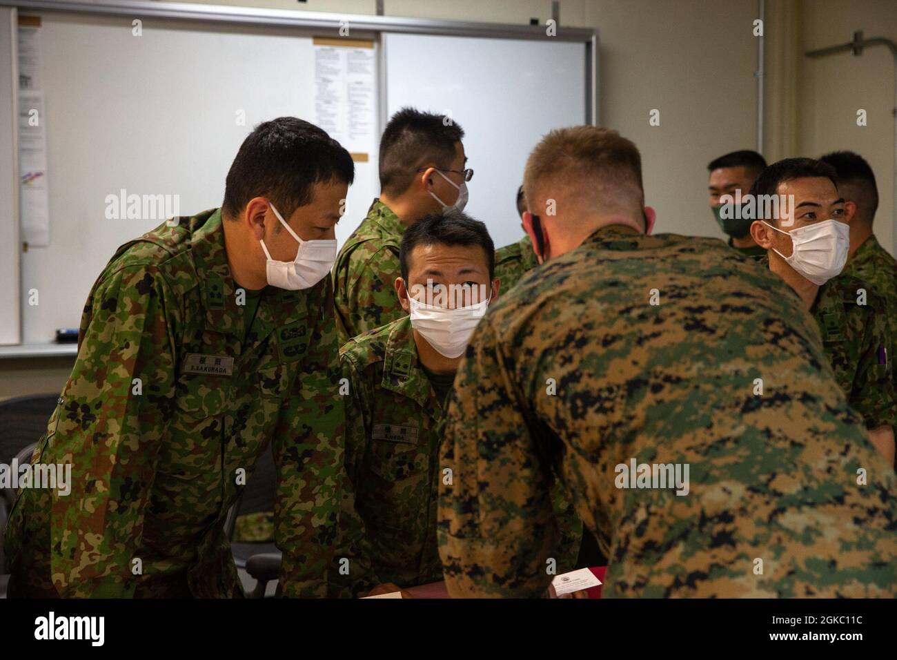 Capt. Shinsaku Sakurada (left), and 1st Lt. Shuhei Ueda (middle), both intelligence officers with 51st Japan Ground Self-Defense Force Regiment, meet with 2nd Lt. Coby Fisher, an intelligence officer with 4th Marine Regiment, during a key leader engagement at Camp Schwab, Okinawa, Japan on March 8, 2021. The discussions were aimed at enhancing interoperability and understanding between 4th Marines and the 51st Regiment. Stock Photo