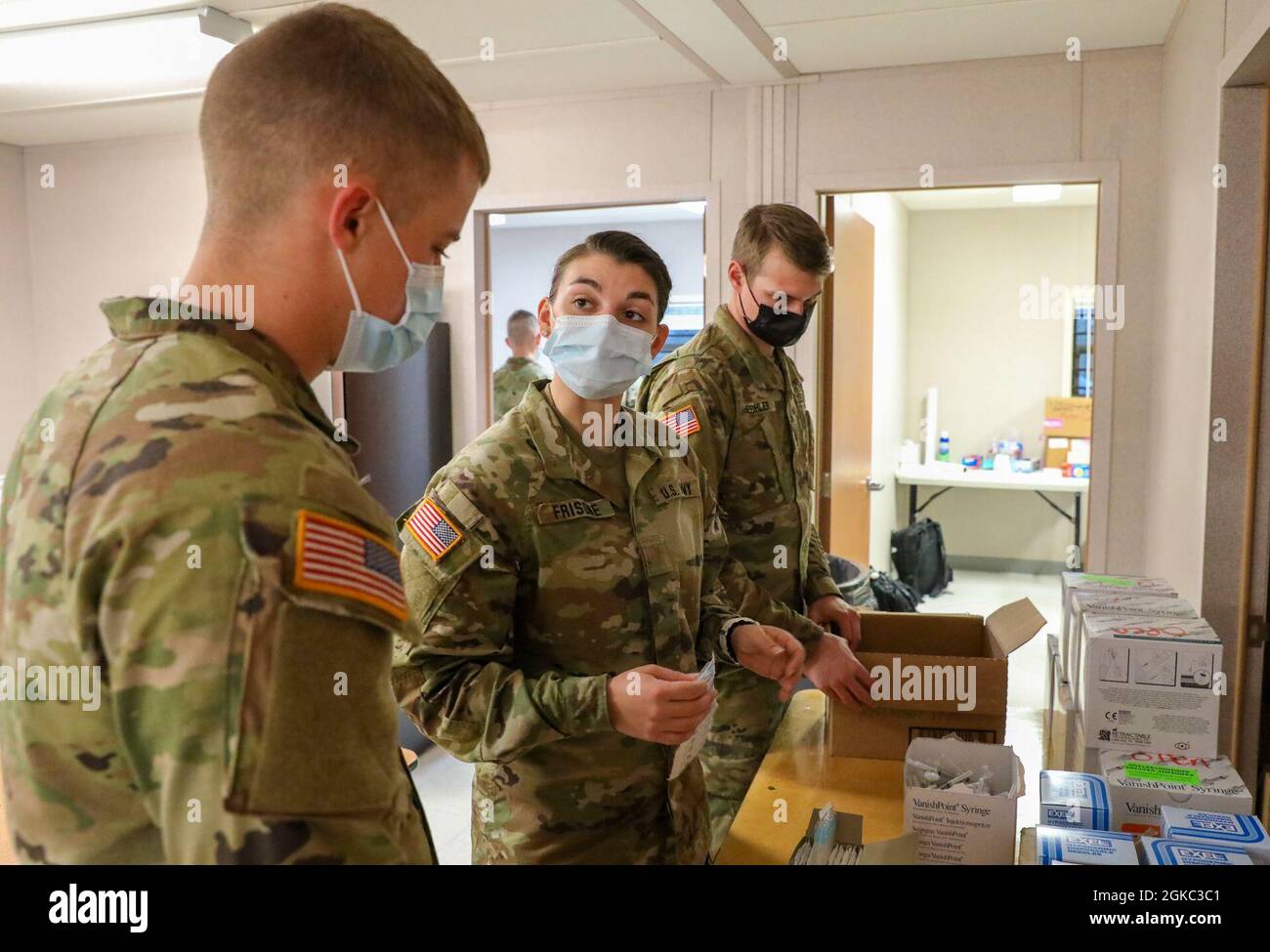 U.S. Army Pfc. Jacob Hoskins (left), a combat medic assigned to 2nd Battalion, 70th Armor Regiment, 2nd Armored Brigade Combat Team, 1st Infantry Division, receives training from U.S. Army 2nd Lt. Maria Frisone (center), a medical surgical nurse at Walter Reed National Medical Center, Bethesda, Maryland, on how to properly assist with preparing COVID-19 vaccinations at the Fair Park Community Vaccination Center in Dallas, March 9, 2021. Through a federal validation process, it was determined that U.S. service members could assist FEMA in its national effort to help vaccinate American citizens. Stock Photo