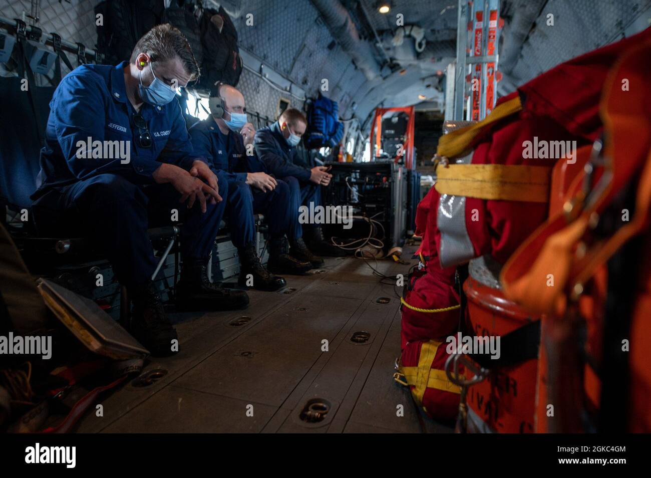 Members with Base Alameda clinic rest during a flight on a Coast Guard Air Station Sacramento C-27J Spartan aircraft from Oakland to San Diego, March 9, 2021. The clinic crew members are responsible for transporting and distributing the vaccines to Coast Guard members in the San Diego area. Stock Photo