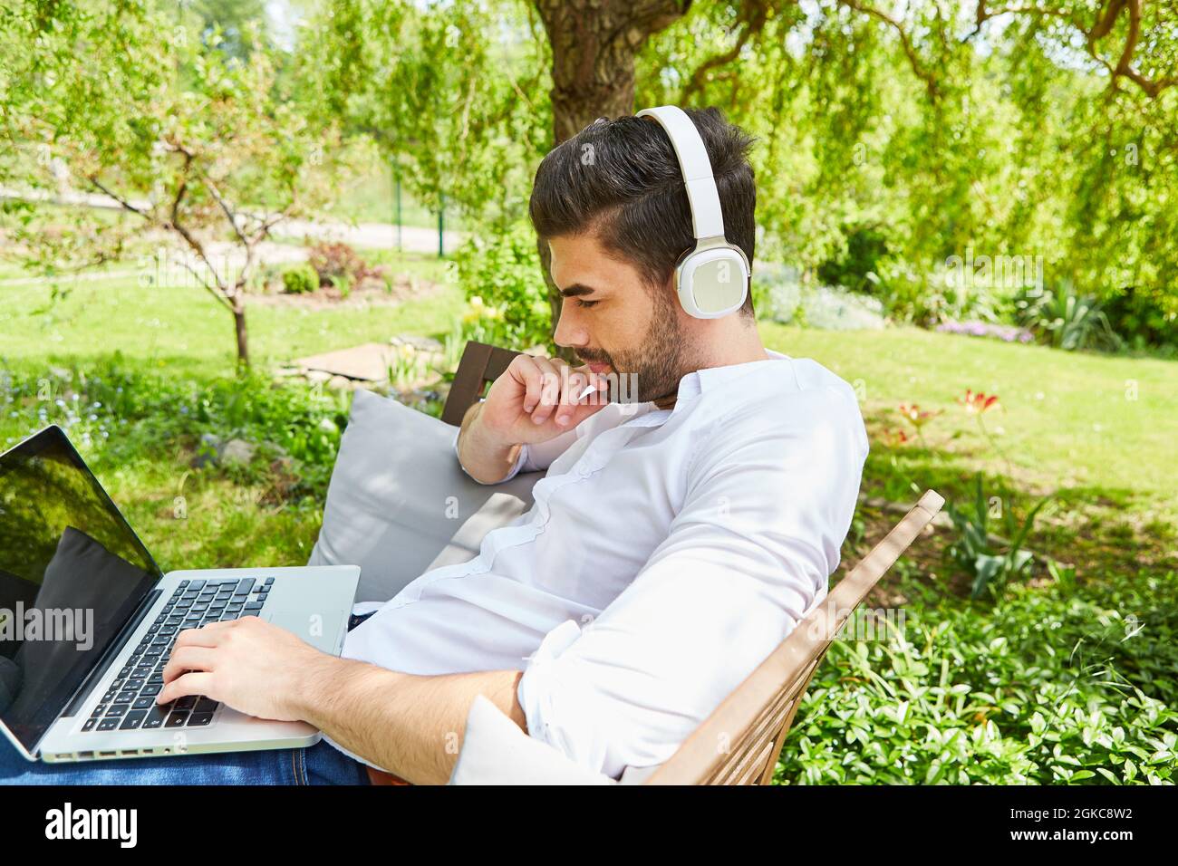 Thoughtful freelancer man working on laptop computer in garden as home office Stock Photo