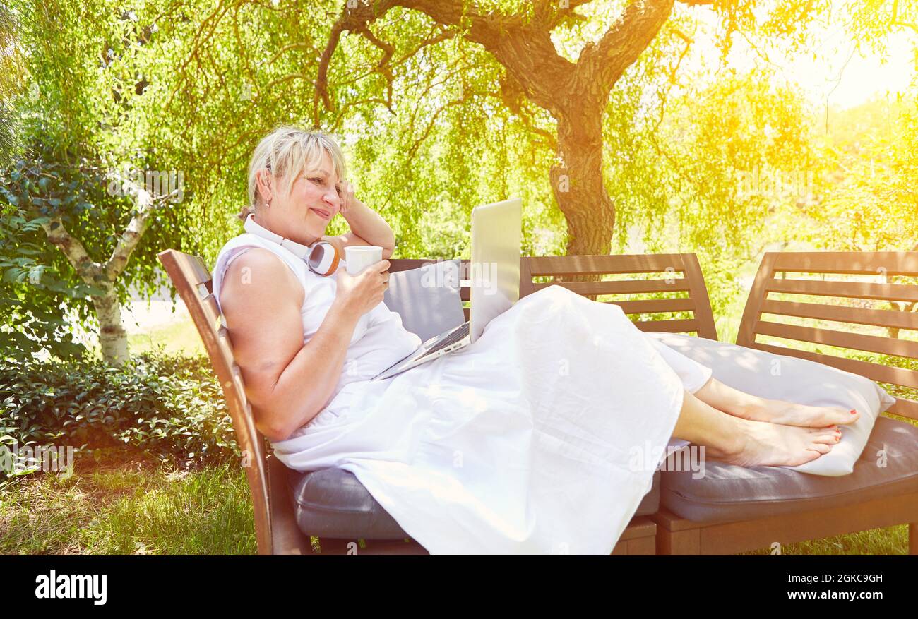 Woman doing home office in the garden in summer with laptop computer Stock Photo