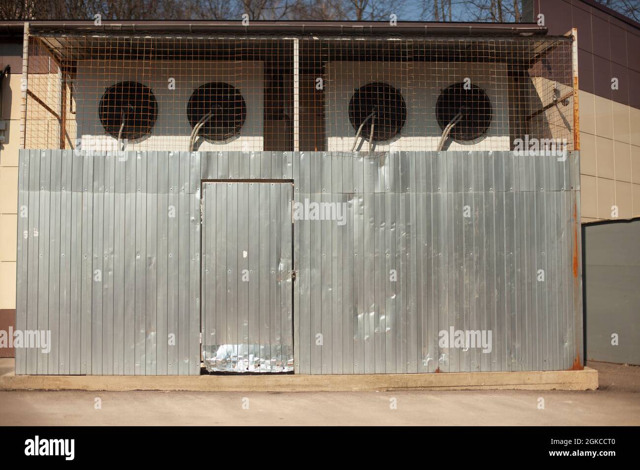 Air conditioners are protected by a grill. Cooling system of the enterprise. Large air filters are enclosed by a metal fence. The backyard of the stor Stock Photo