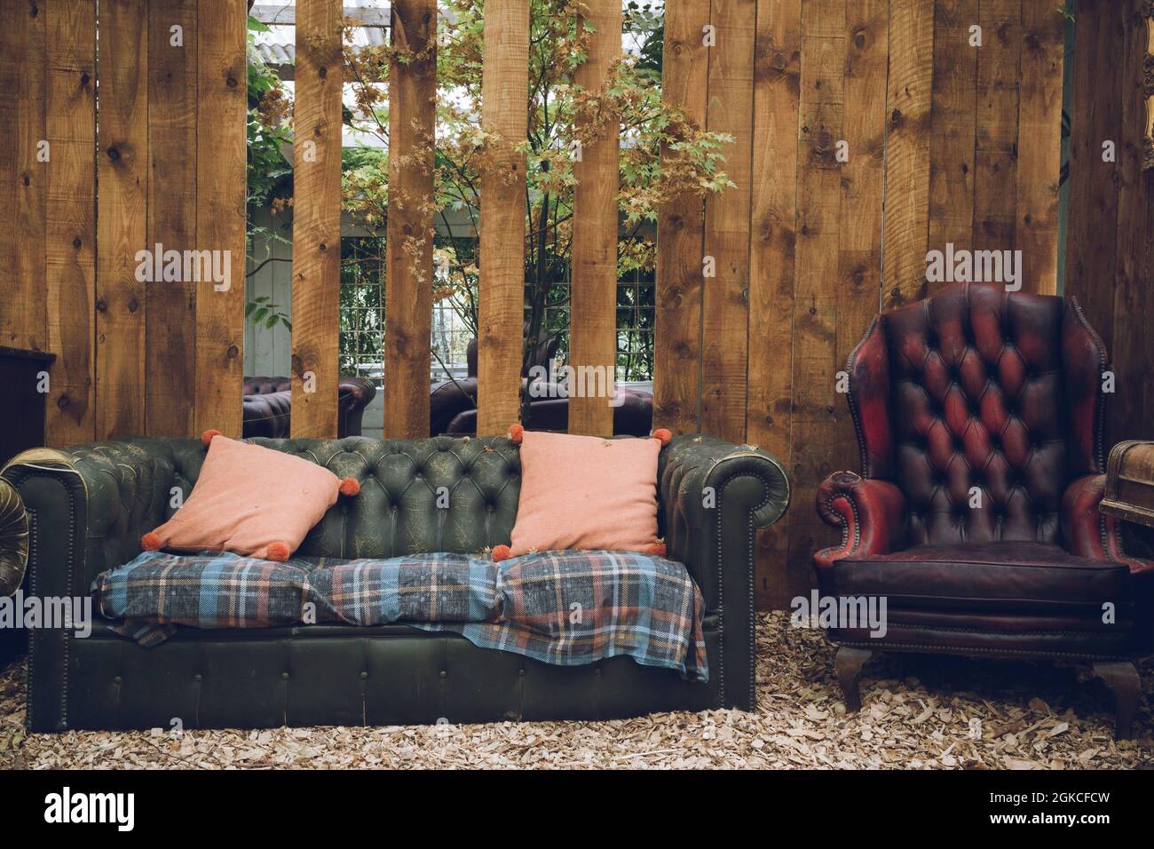 A rustic looking antique sofa in front of a weathered wooden wall Stock Photo