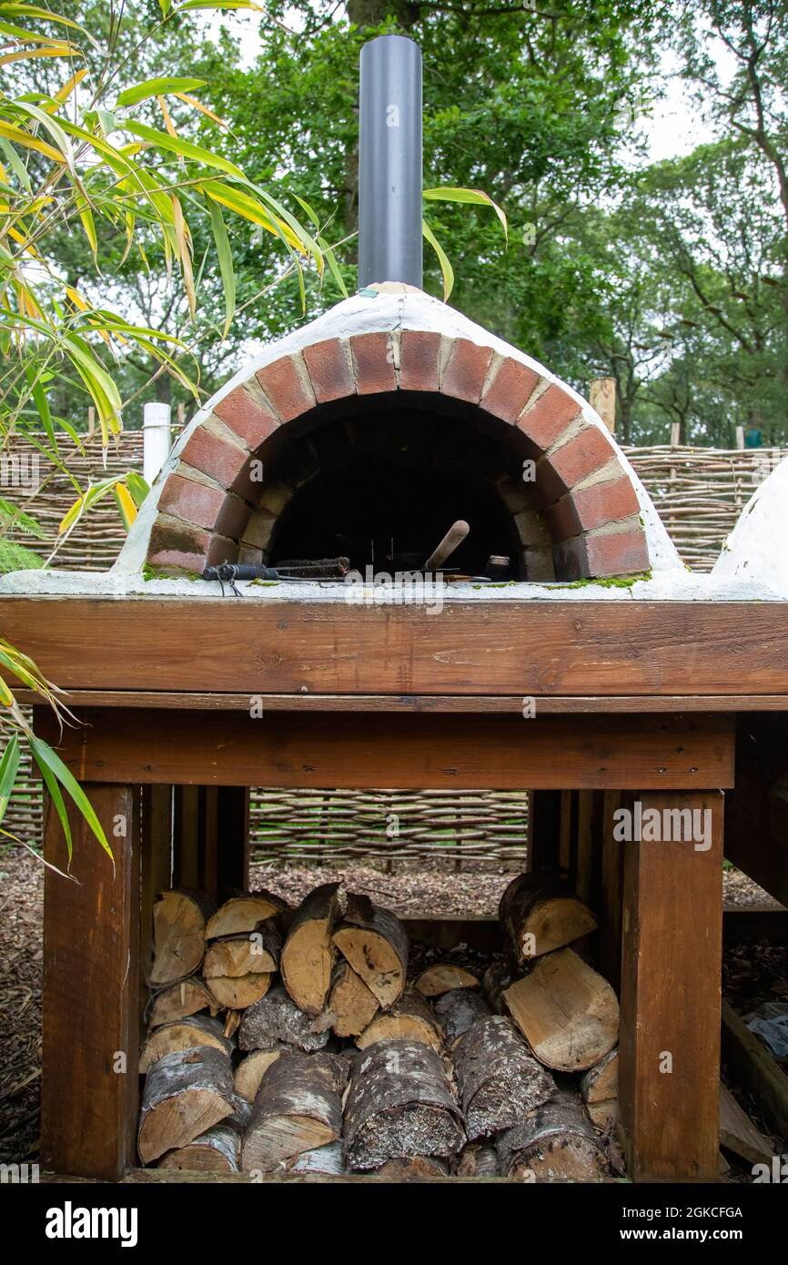 a pizza oven with logs stacked underneath Stock Photo