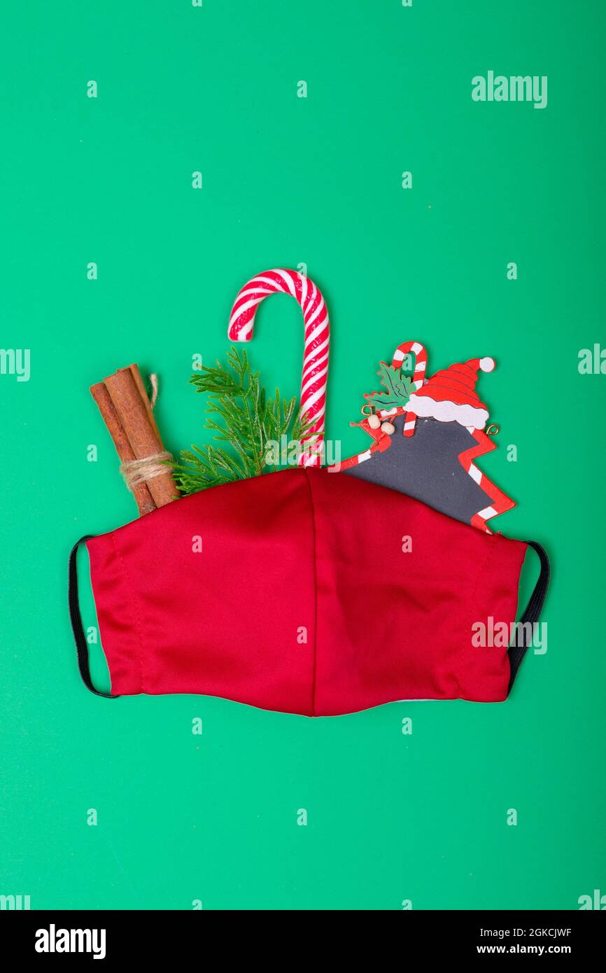 Composition of red face mask with christmas decorations on green background Stock Photo
