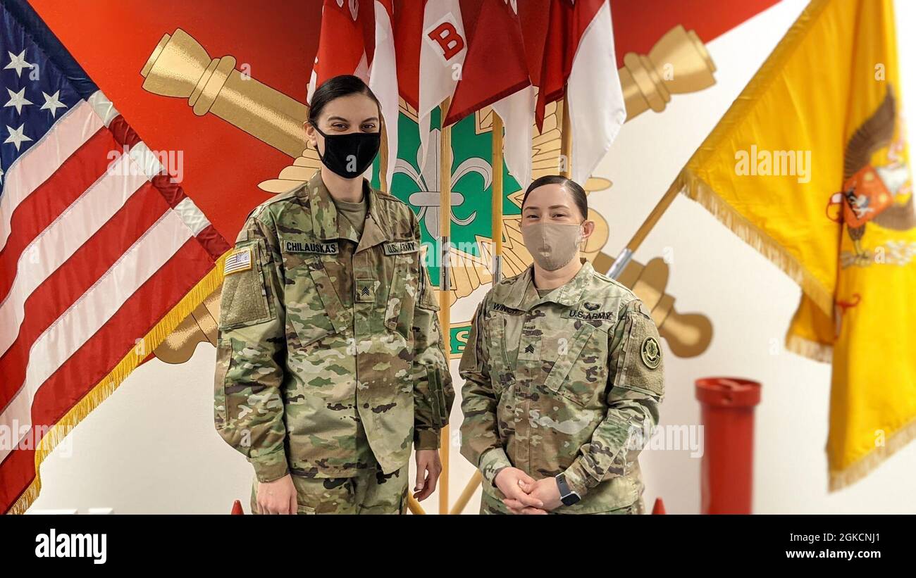 U.S. Army Sgt. Jennifer Ponce and Sgt. Kelley Chilauskas stand in front of  the unit colors