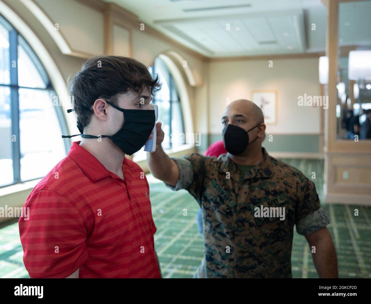 A U.S. Navy Corpsman with Task Force Commitment checks a recruit's temperature at the Hyatt Regency hotel in Jacksonville, Florida, March 15, 2021. Task Force Commitment service members, mostly comprised of Marine Forces Reserve Marines and Sailors, ensure recruits are quarantined at the hotel for two weeks to mitigate the spread of COVID-19 before traveling to Marine Corps Recruit Depot Parris Island to begin recruit training. Stock Photo