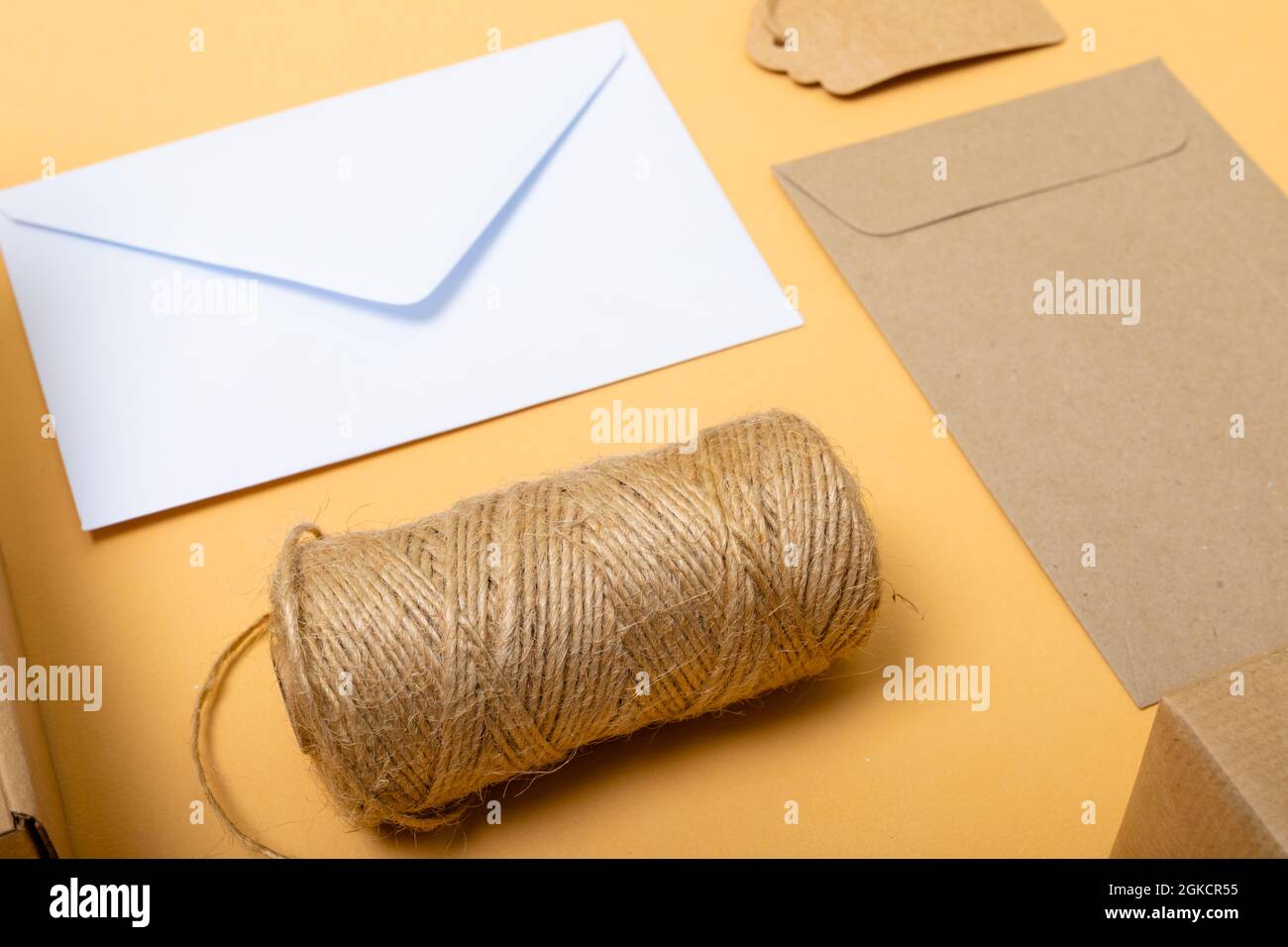 Composition of rope, envelopes and gift tag on yellow background Stock Photo