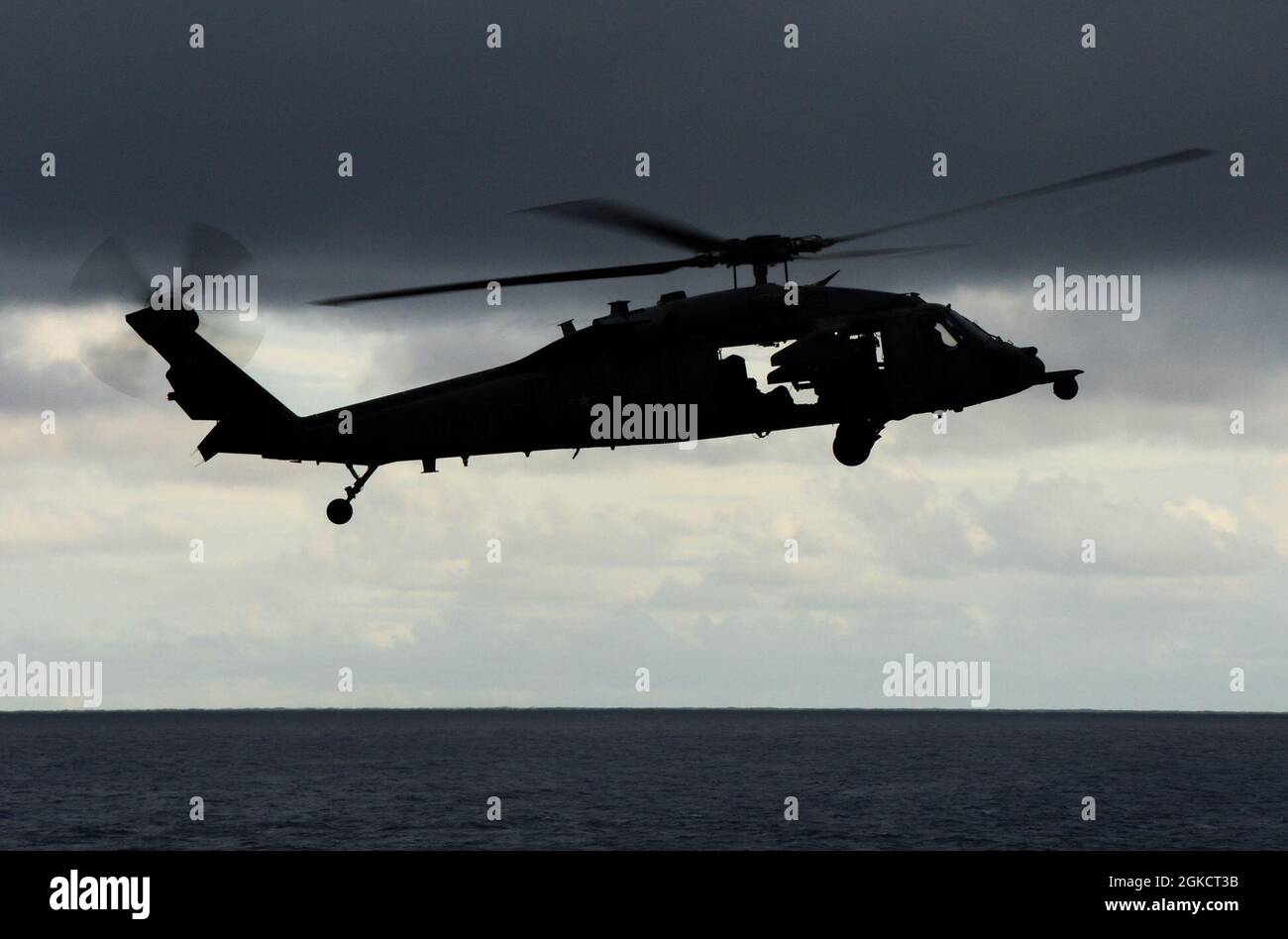 INDIAN OCEAN (March 15, 2021) An MH-60S Sea Hawk, assigned to the “Eightballers” of Helicopter Sea Combat Squadron (HSC) 8, flies near the Arleigh Burke-class guided-missile destroyer USS Russell (DDG 59) during a vertical replenishment March 15, 2021. Russell, part of the Theodore Roosevelt Carrier Strike Group, is on a scheduled deployment to the U.S. 7th Fleet area of operations. As the U.S. Navy’s largest forward-deployed fleet, 7th Fleet routinely operates and interacts with 35 maritime nations while conducting missions to preserve and protect a free and open Indo-Pacific Region. Stock Photo