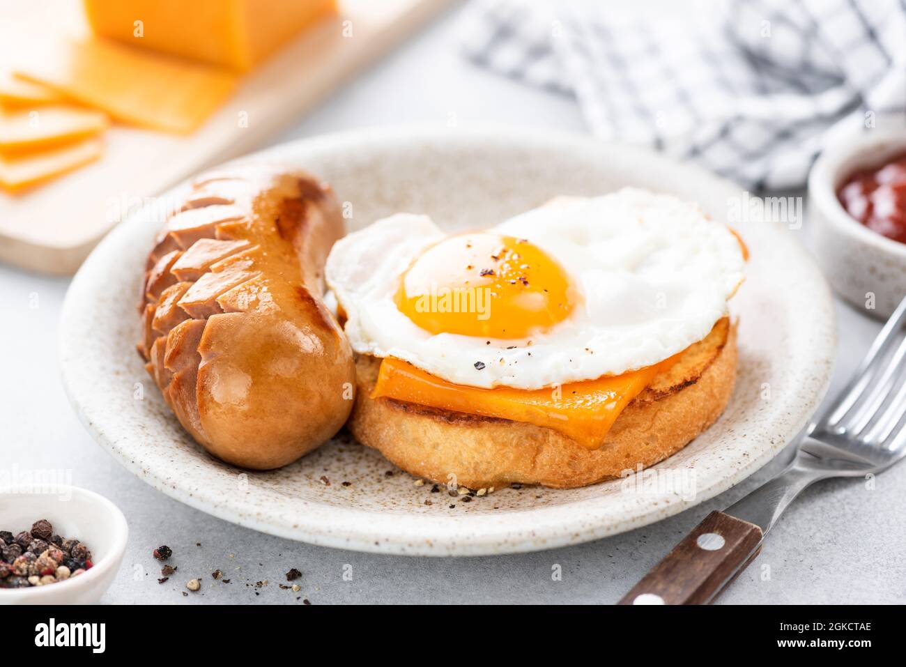 Tasty breakfast toast with cheese, egg and sausage on a plate. English breakfast food in cafe Stock Photo