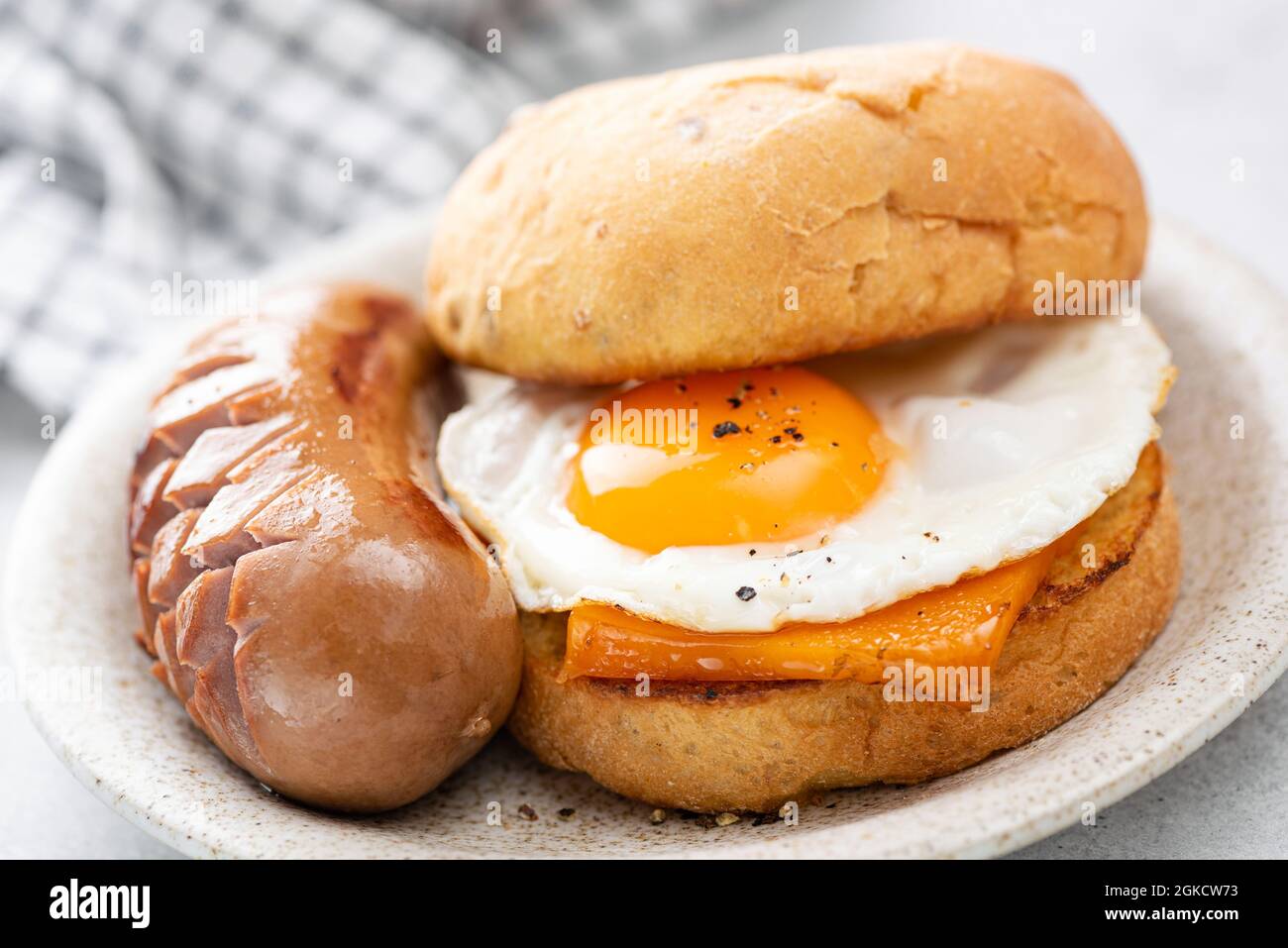 Breakfast sandwich with cheese, egg and sausage. English breakfast food closeup view. Unhealthy eating Stock Photo